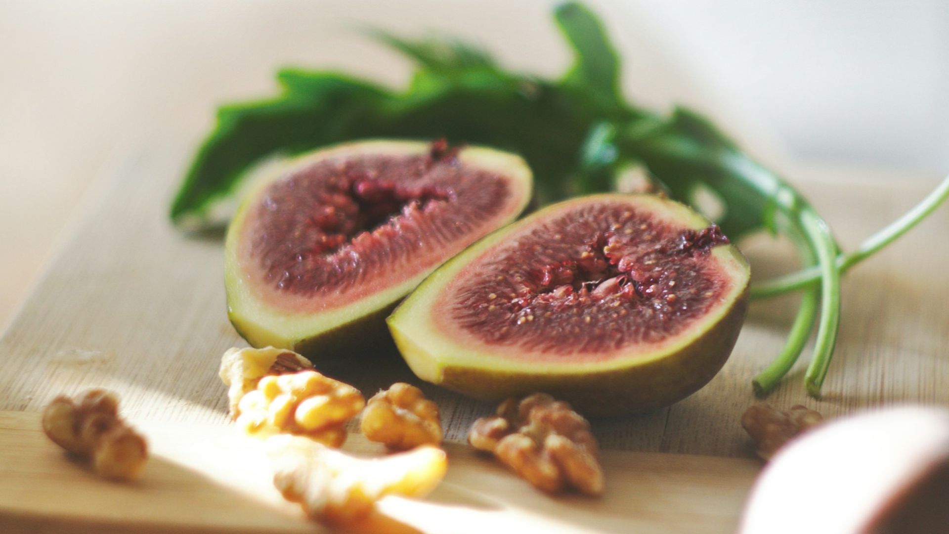 sliced in half oval green fruit above wooden chopping board