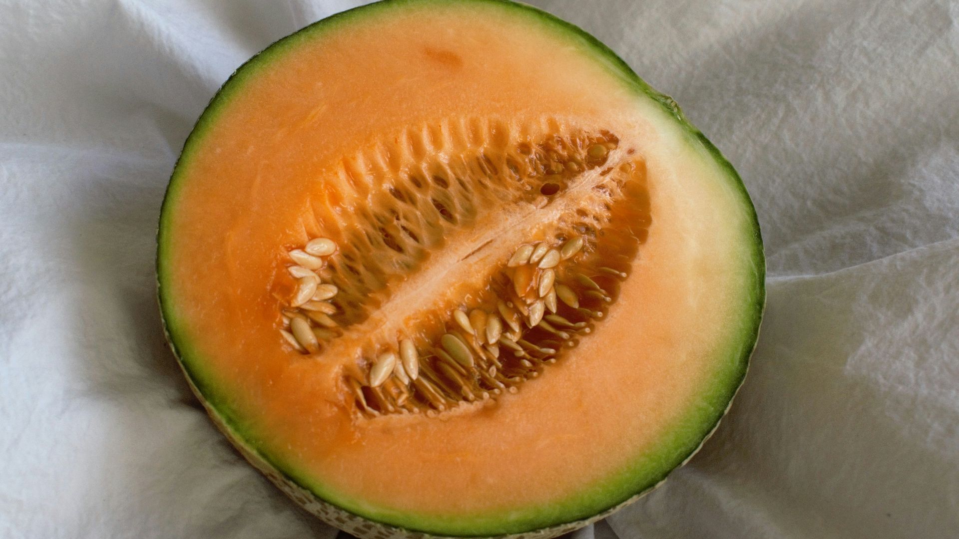 a cut in half melon sitting on top of a white cloth