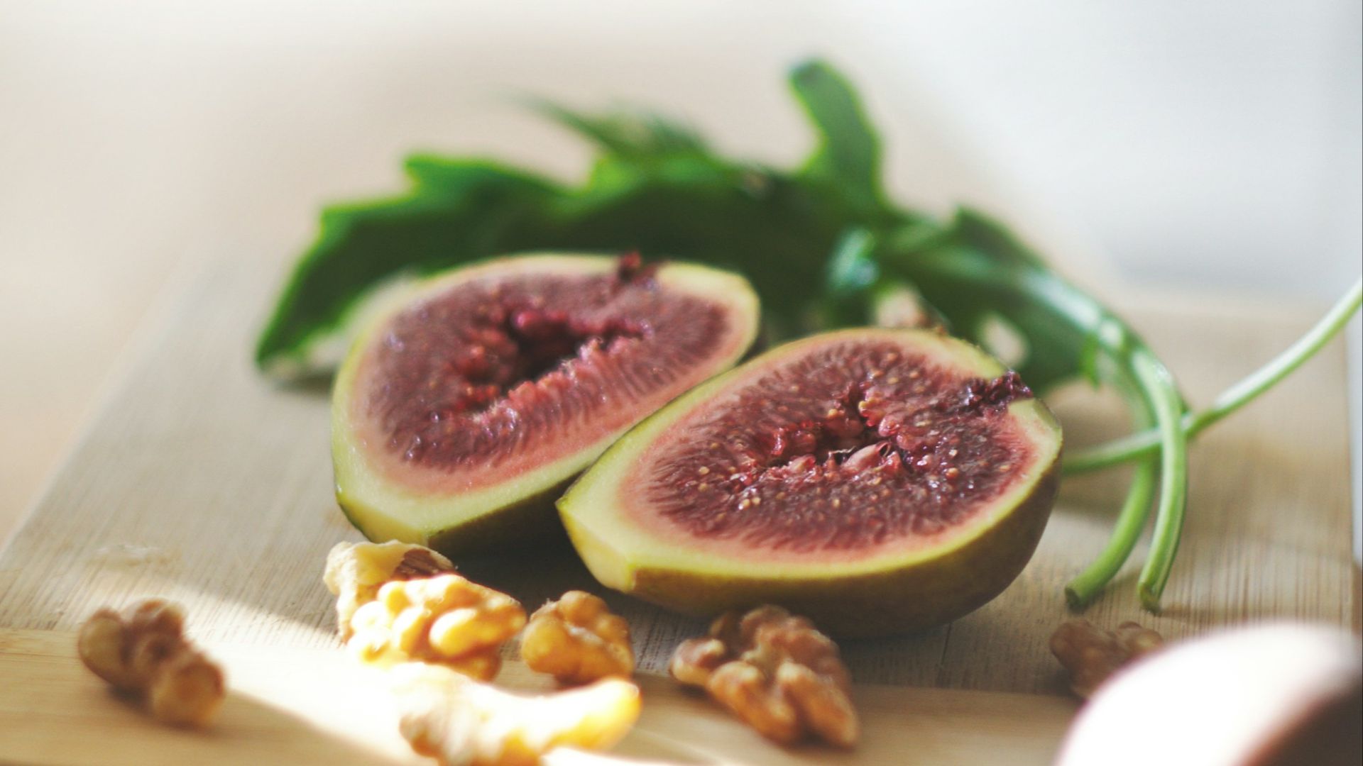 sliced in half oval green fruit above wooden chopping board
