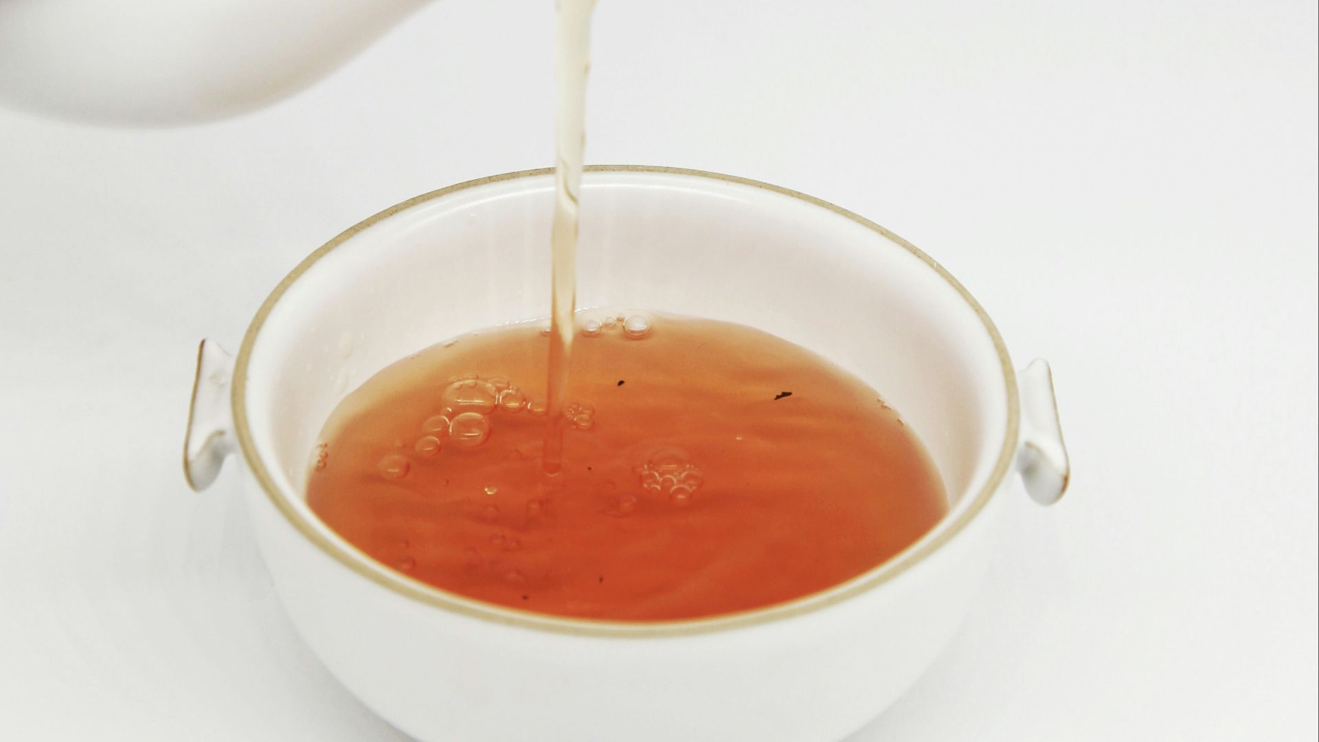 tea pours into white teacup