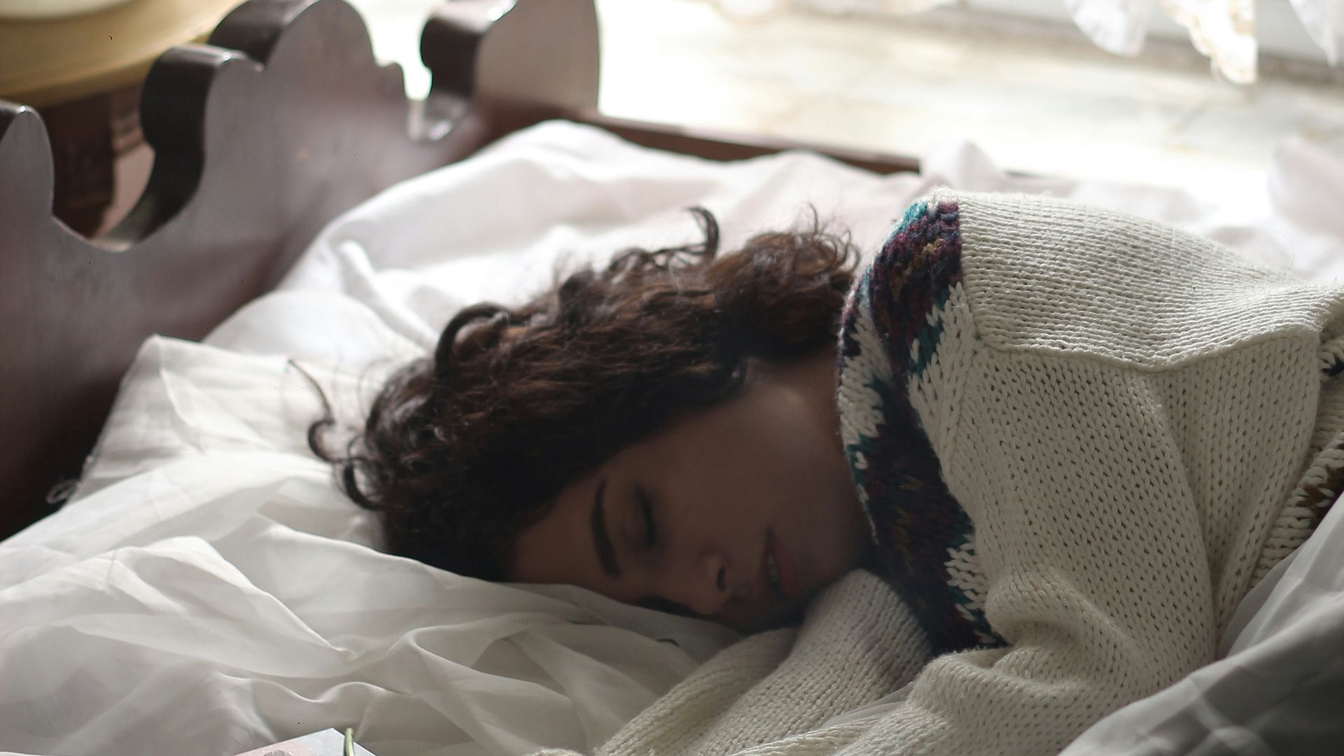 woman sleeping on bed beside book