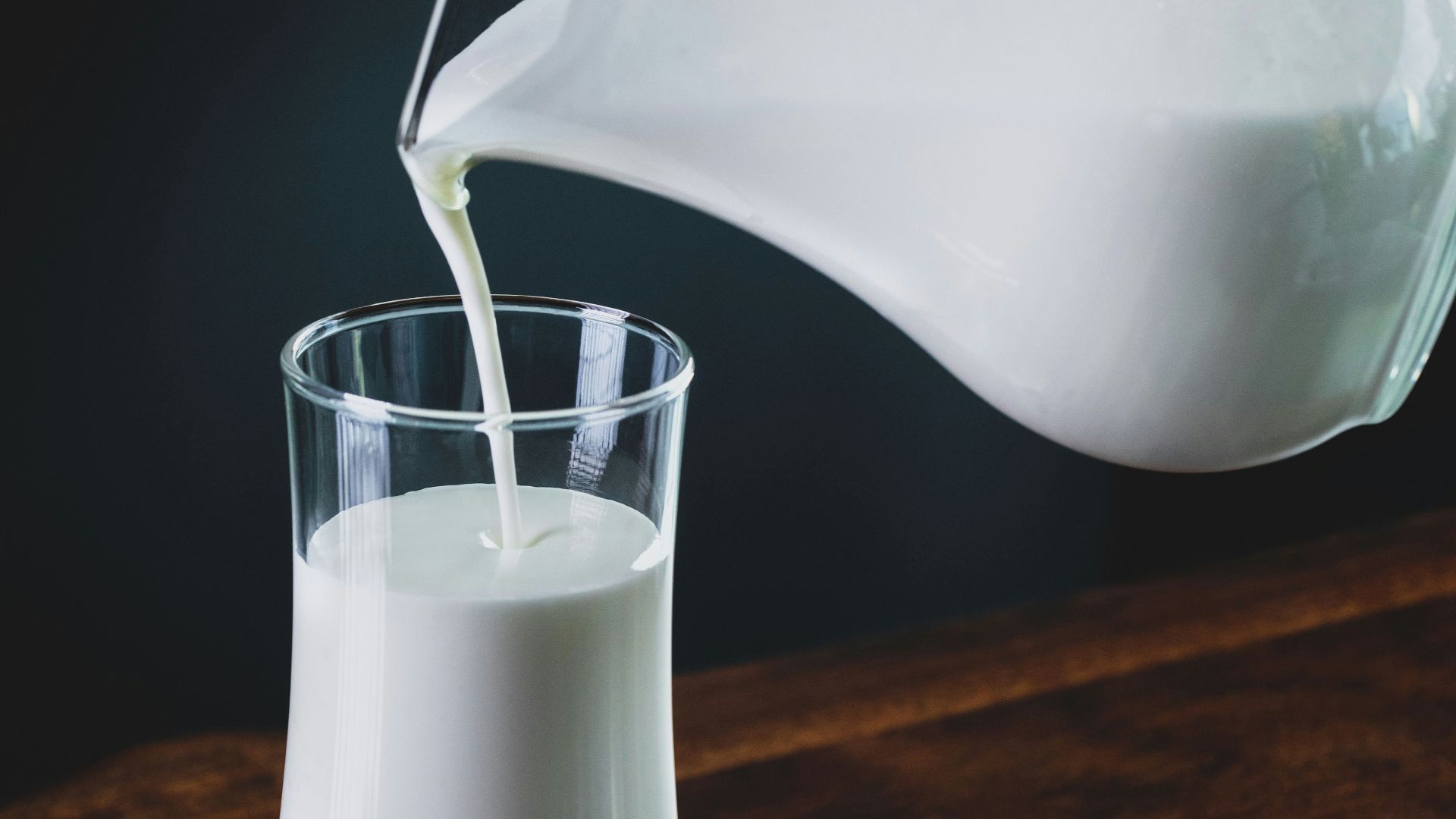 person pours milk into glass