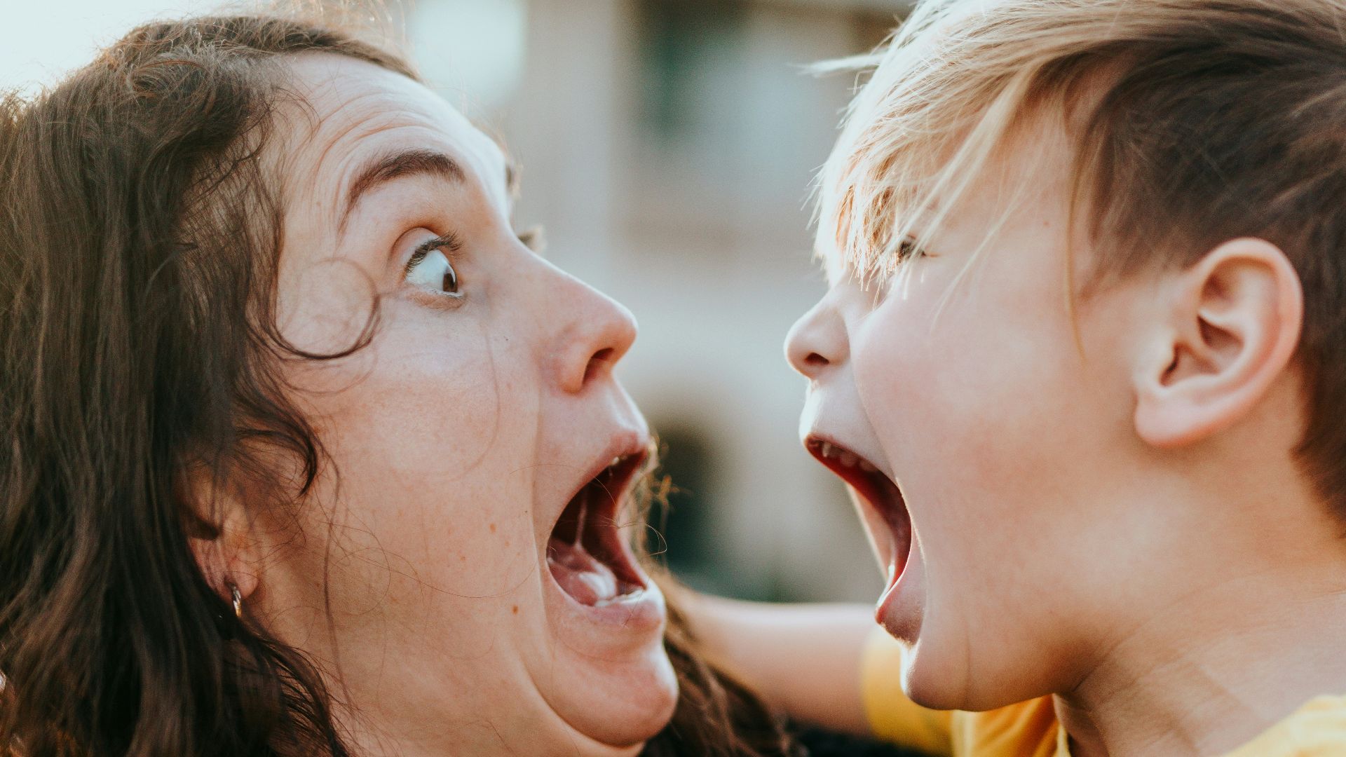 woman in black sweater kissing girl in yellow shirt
