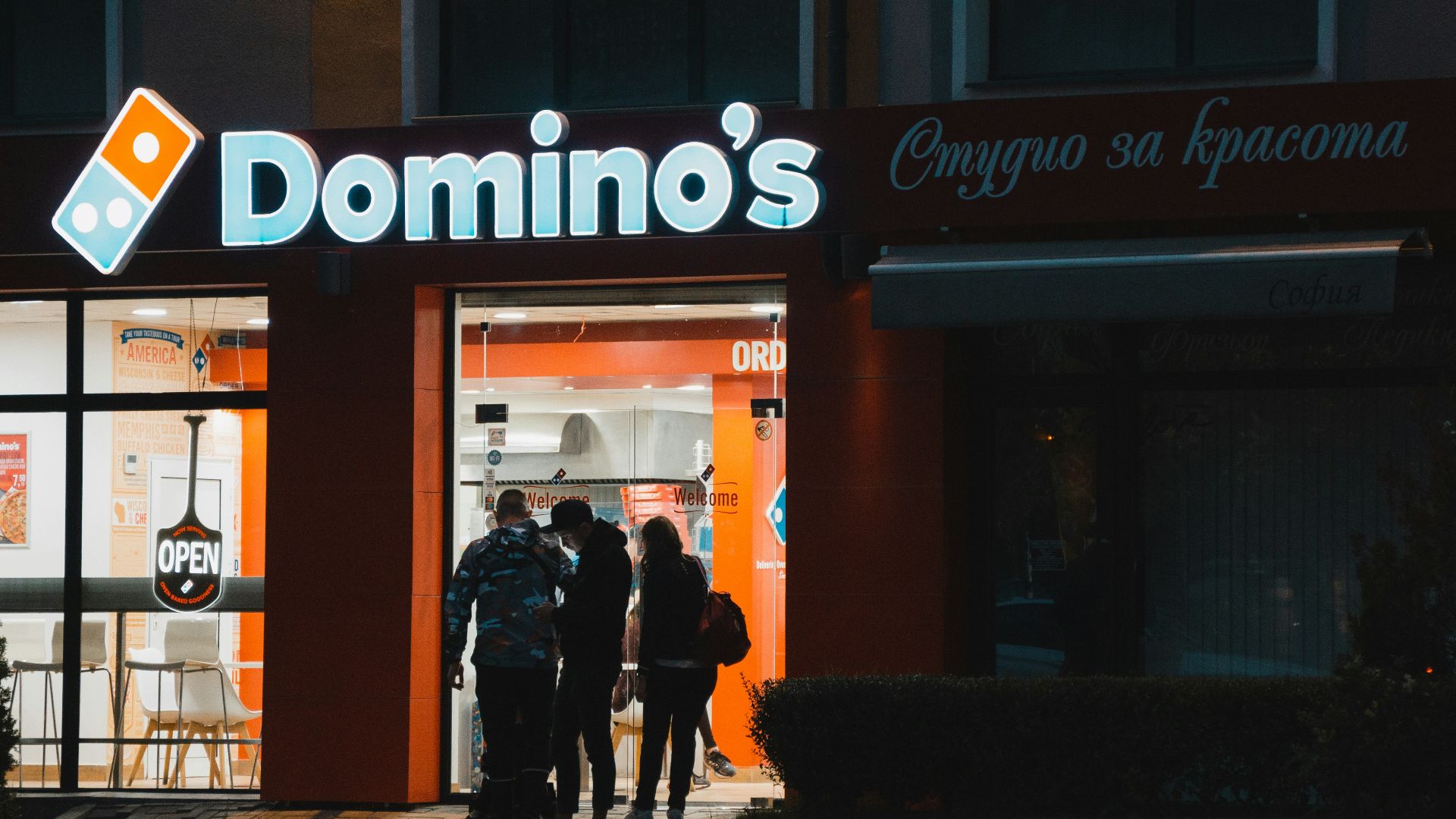 a group of people standing outside of a domino's store