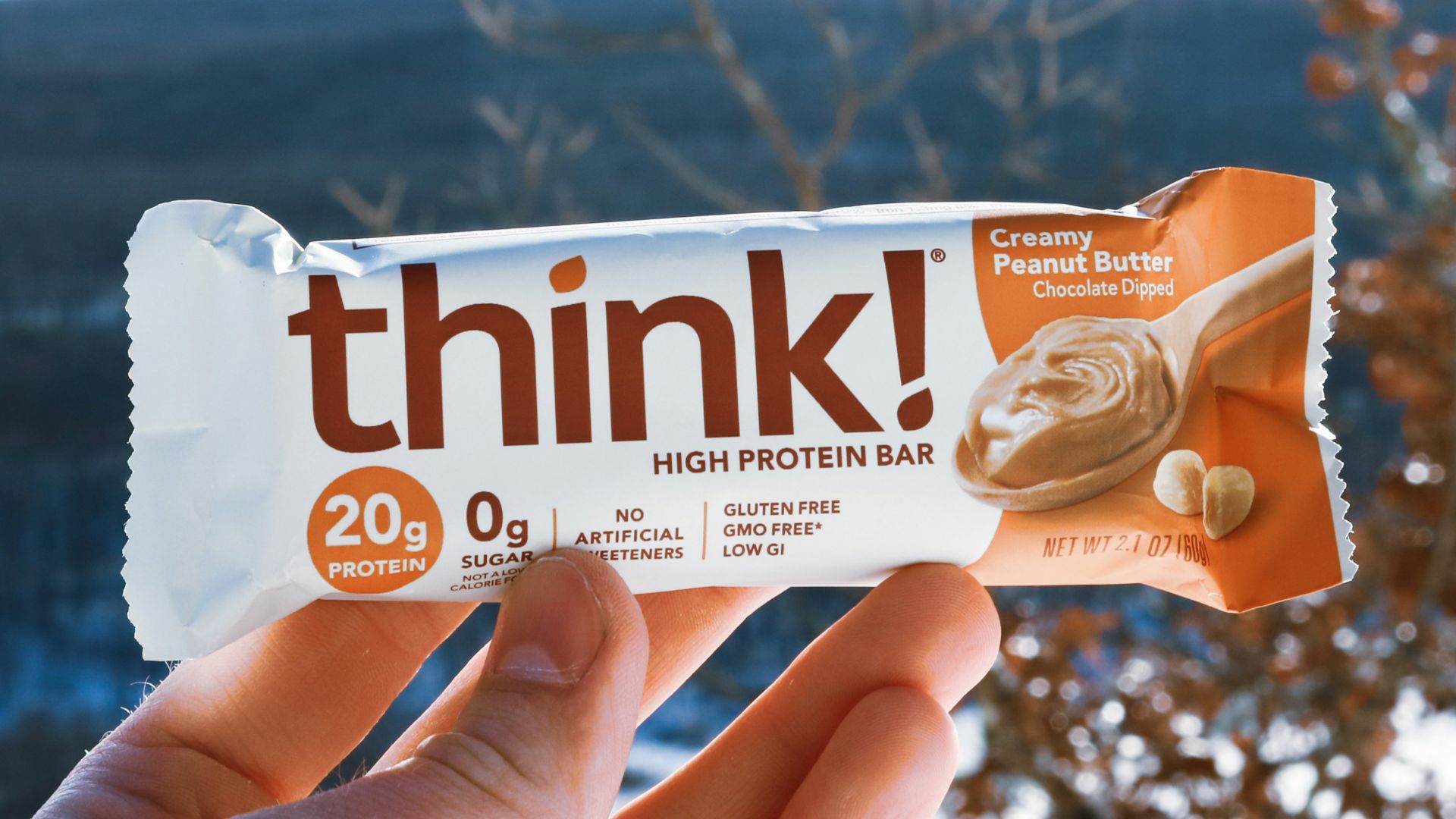 a hand holding a bar of think with a mountain in the background