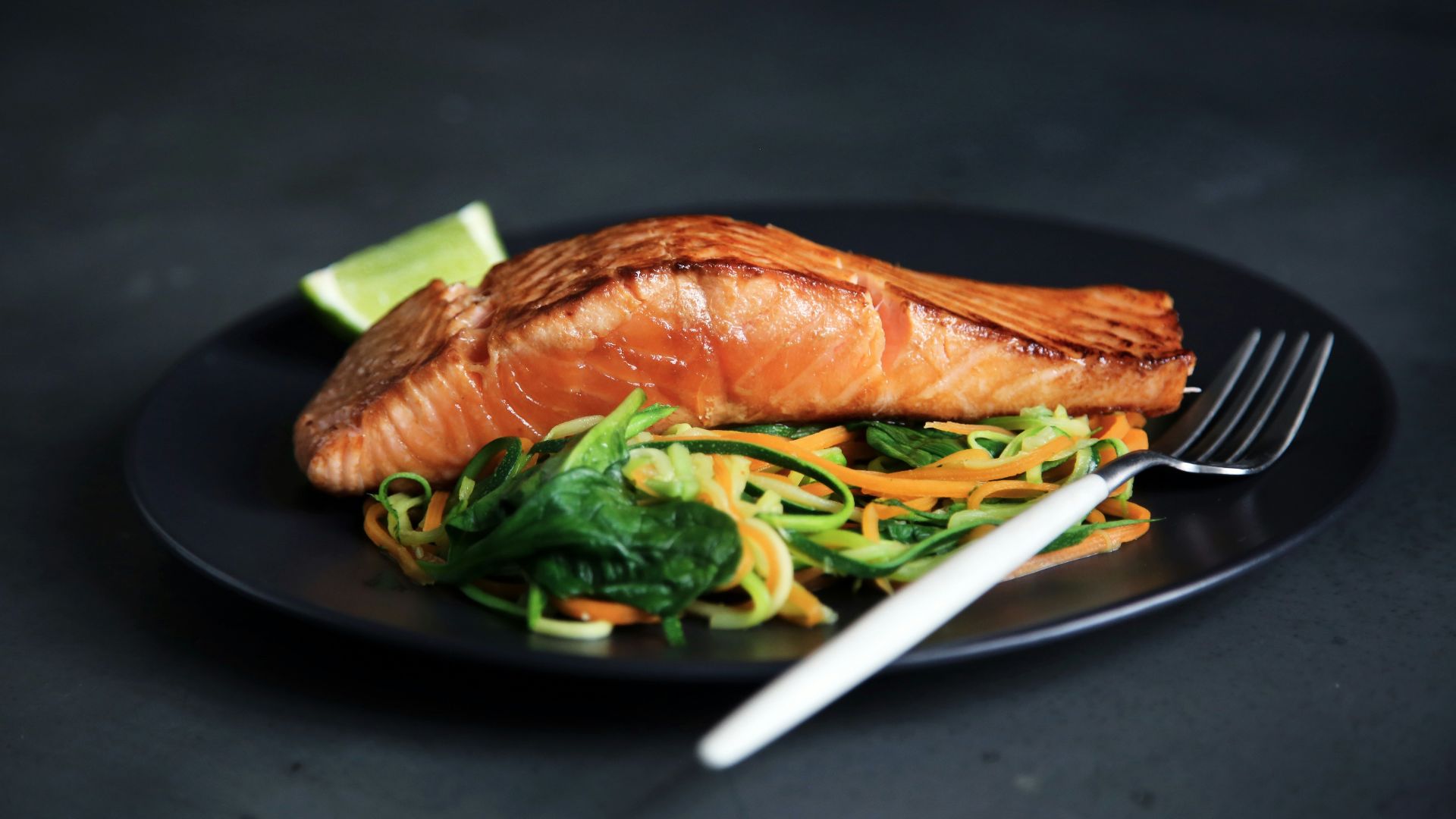 grilled fish, cooked vegetables, and fork on plate