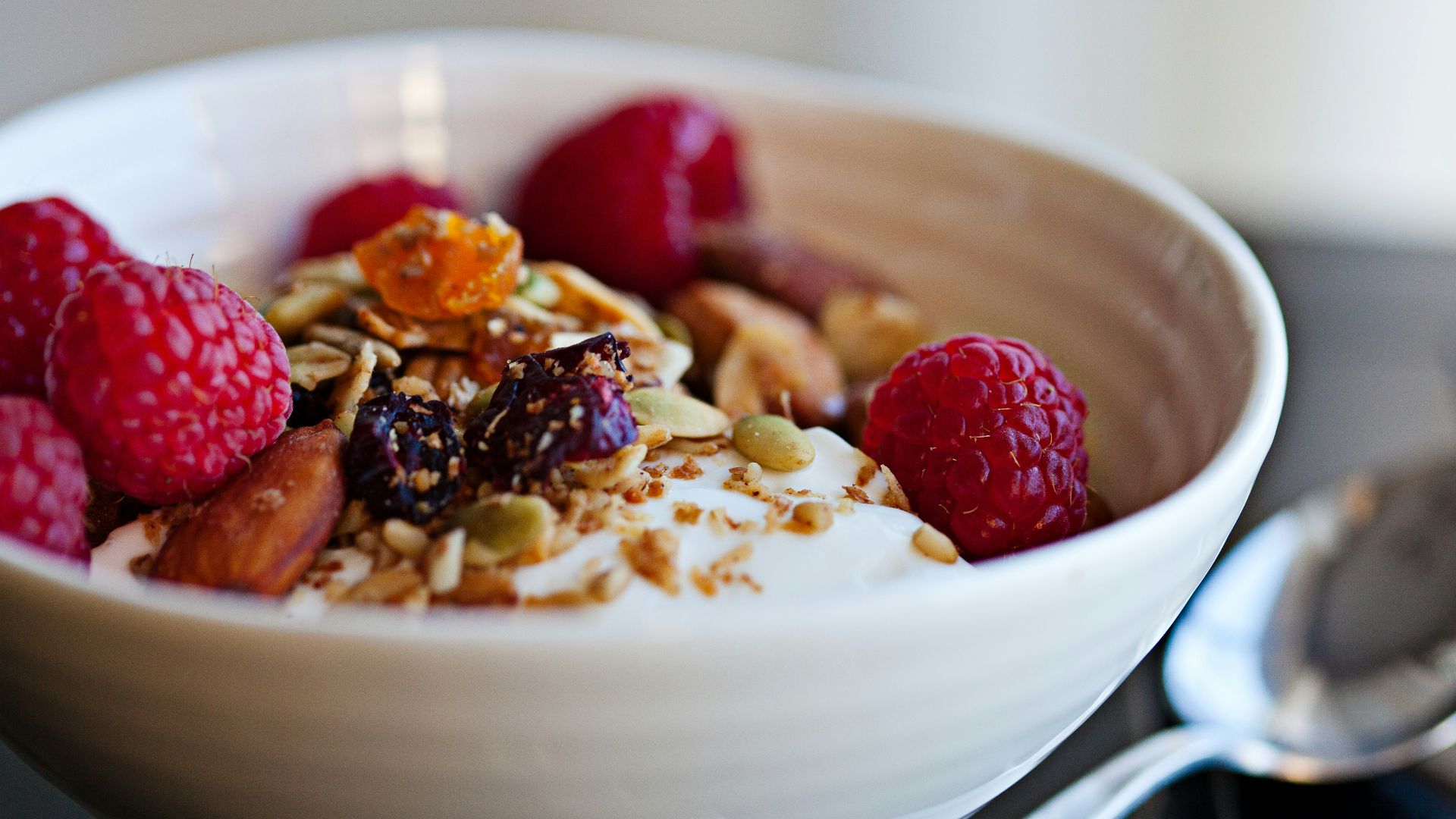a bowl of granola with raspberries and nuts