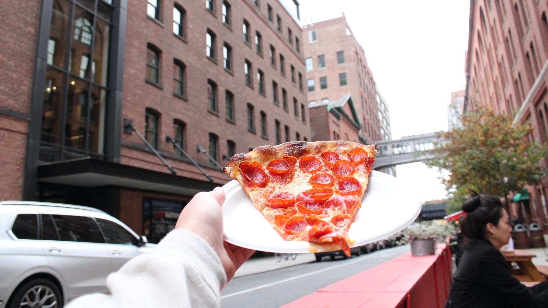 a person holding a plate with a slice of pizza on it