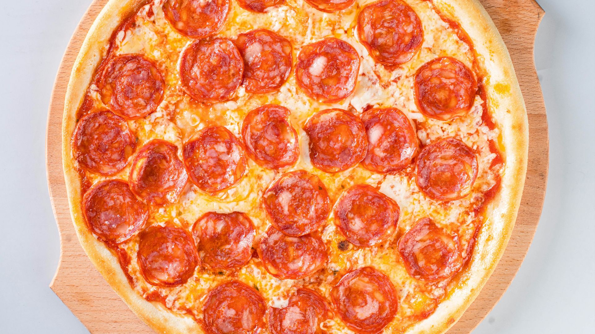a pepperoni pizza sitting on top of a wooden cutting board