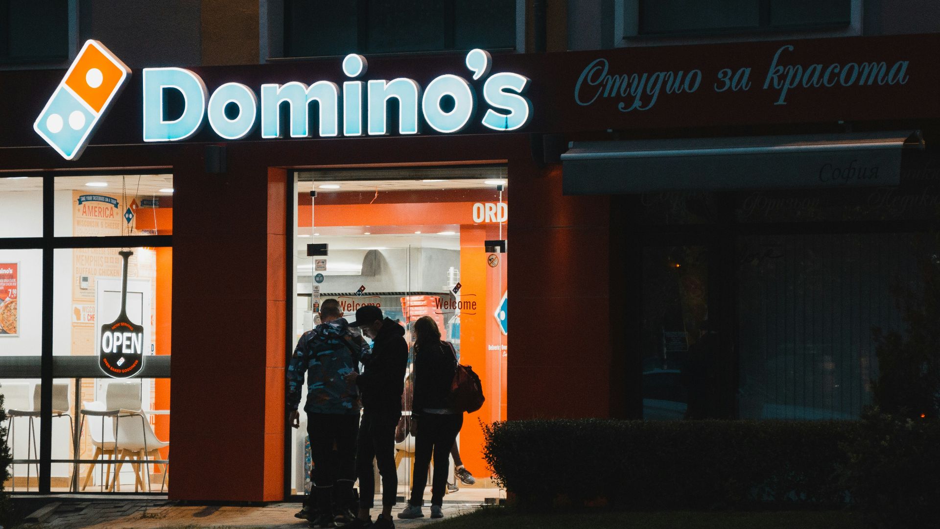 a group of people standing outside of a domino's store