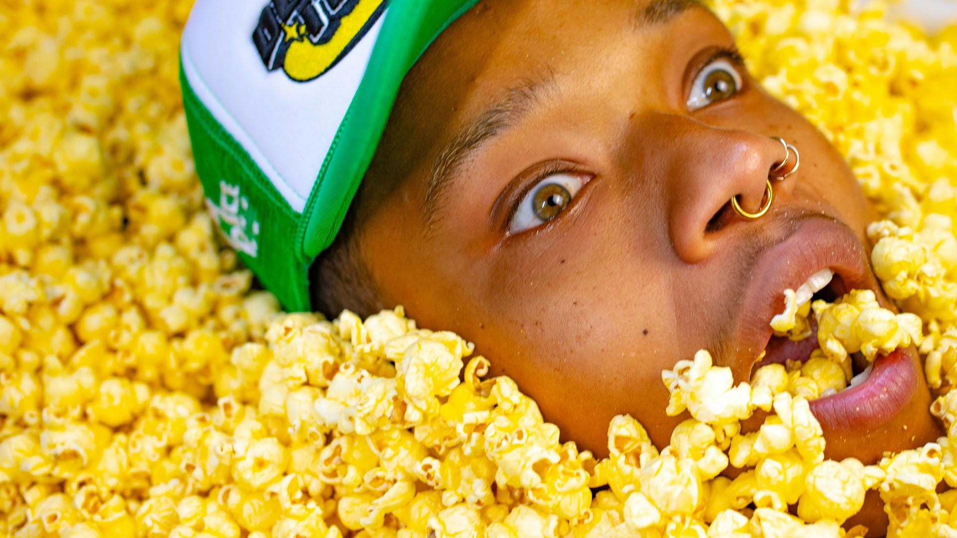 a man with a green hat is in a pile of popcorn