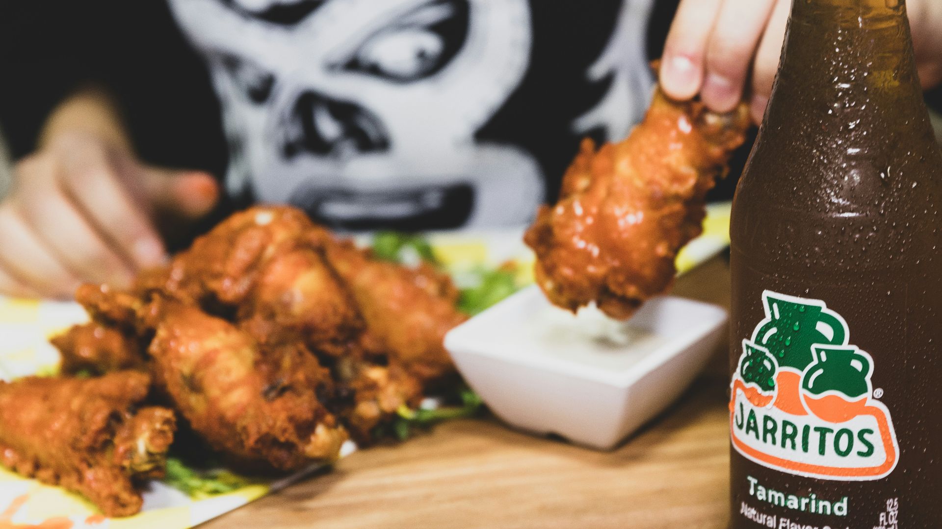 a person holding a bottle of beer over a plate of food