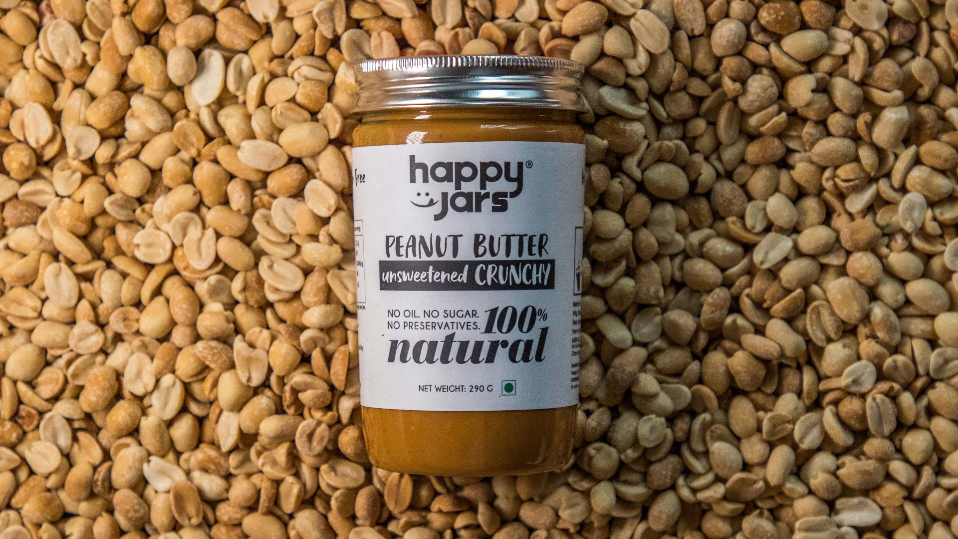 a jar of peanut butter sitting on top of a pile of peanuts