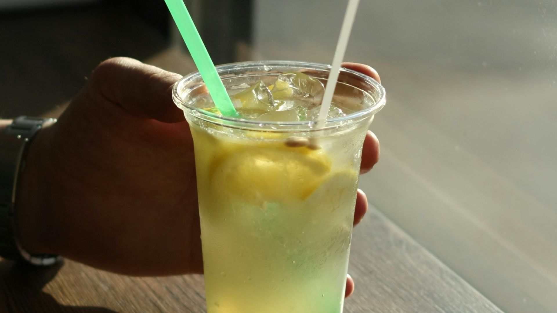 person holding clear drinking glass with yellow liquid