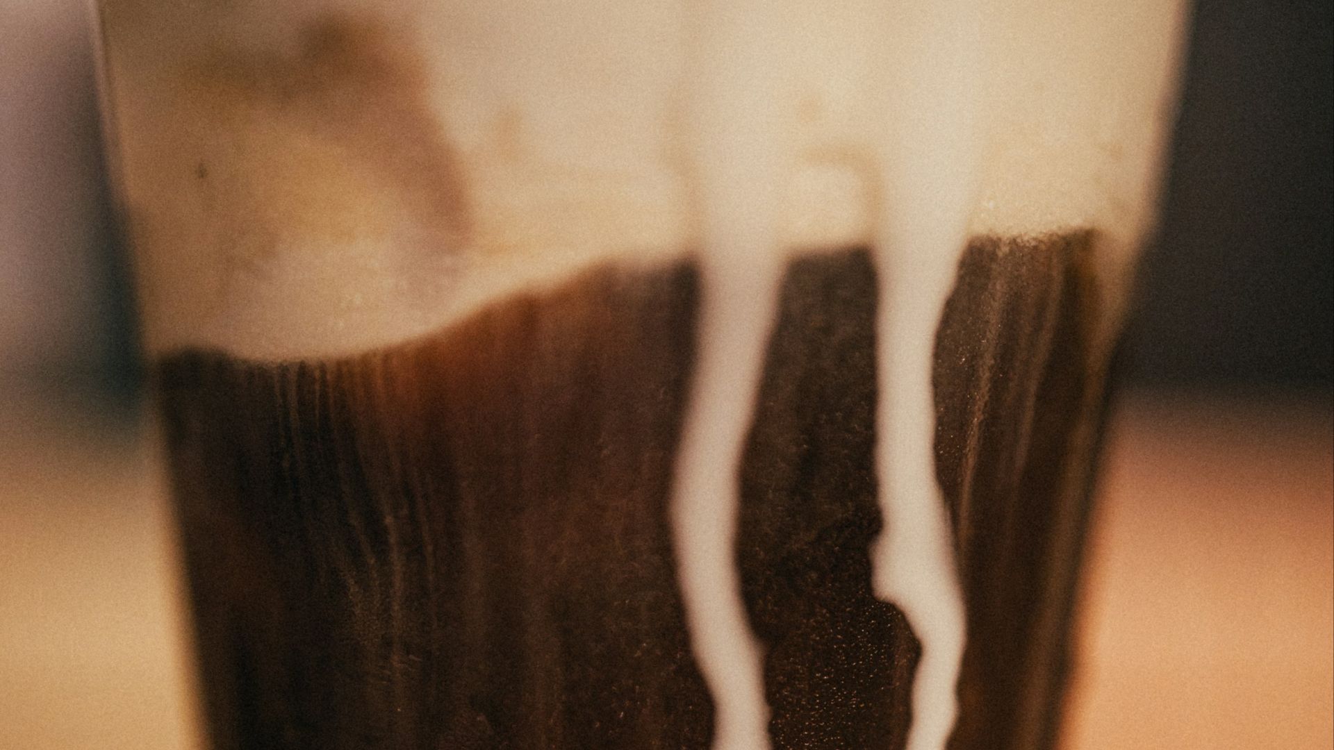 A chocolate drink with white streaks in a tall glass