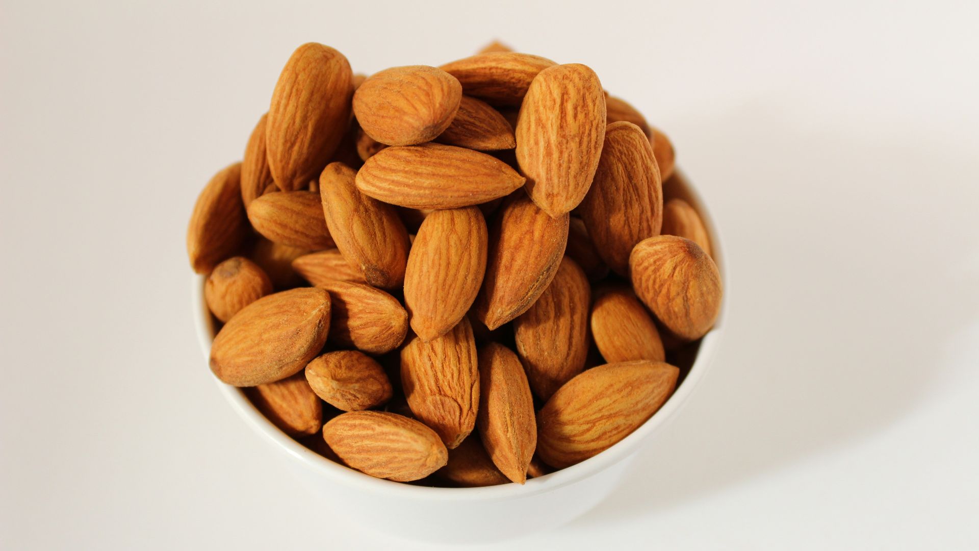 brown almond nuts on white ceramic bowl