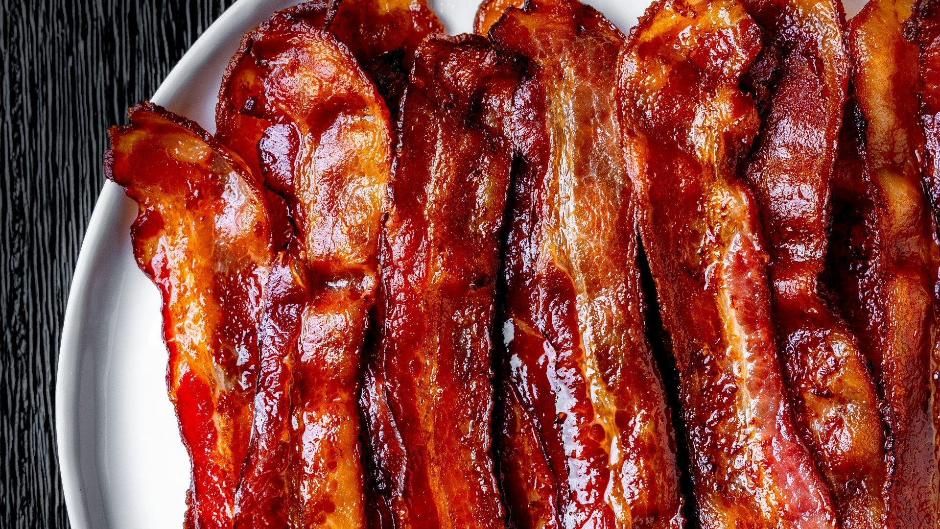 a white plate topped with bacon strips on top of a table