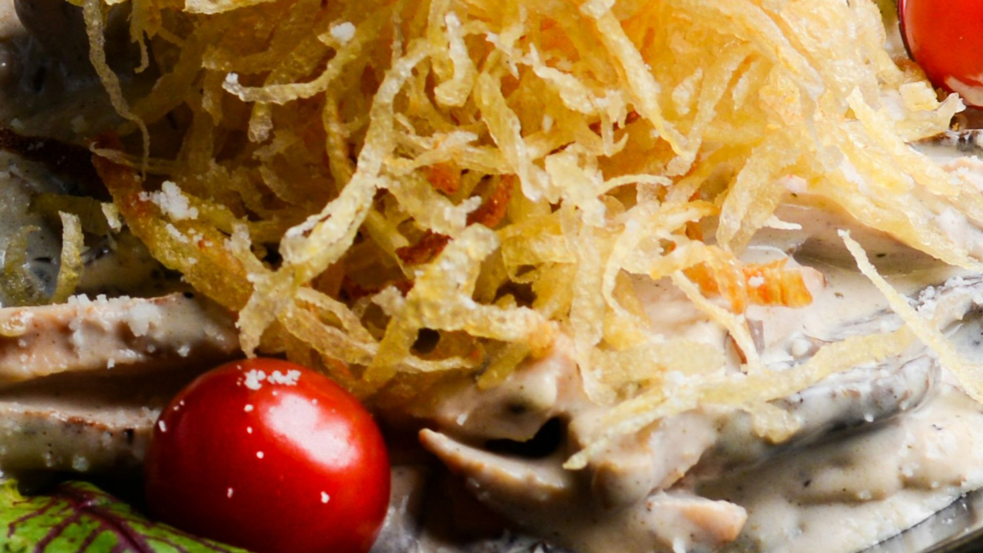 a black plate topped with pasta and tomatoes