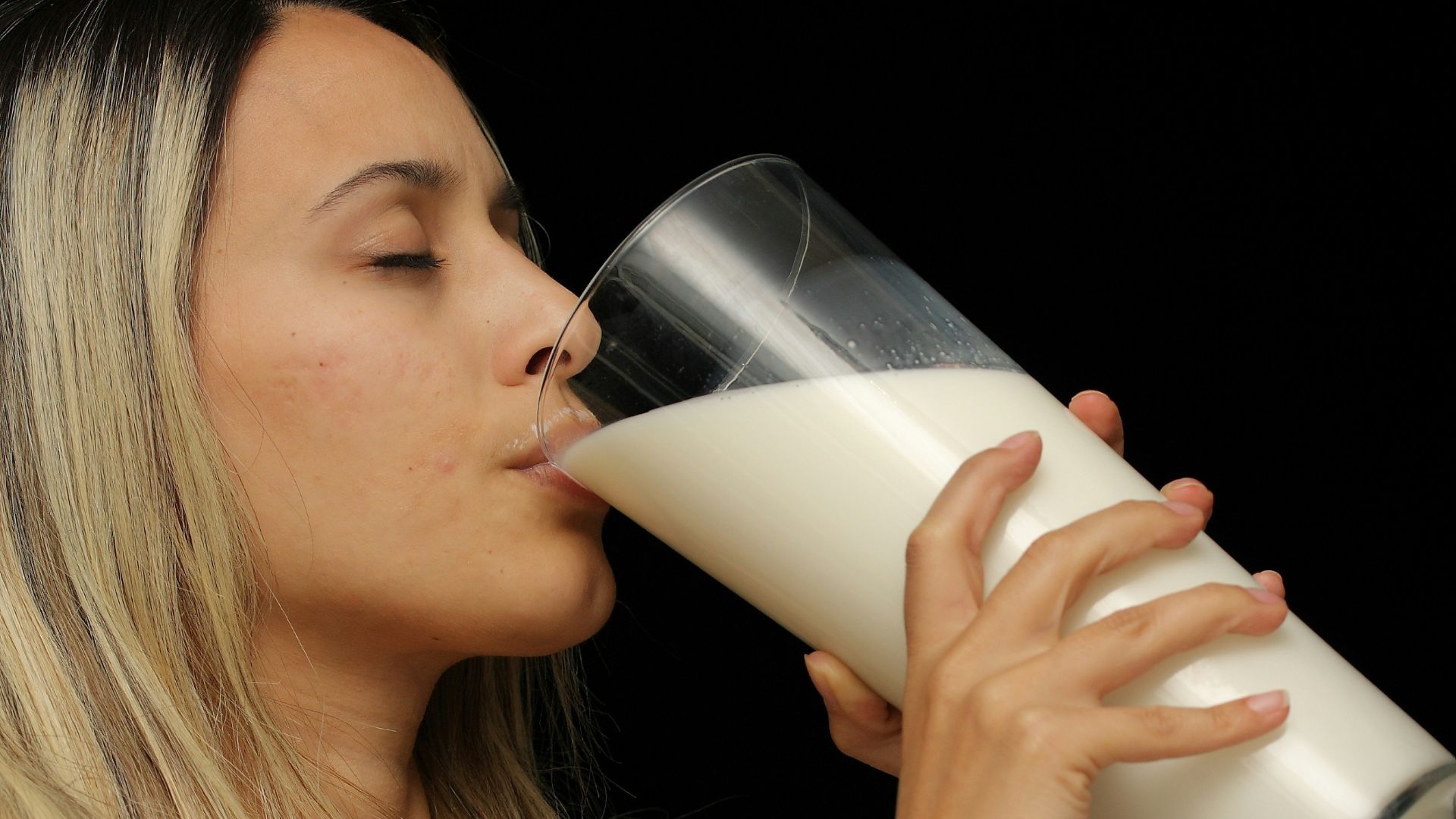 woman drinking milk from clear drinking glass
