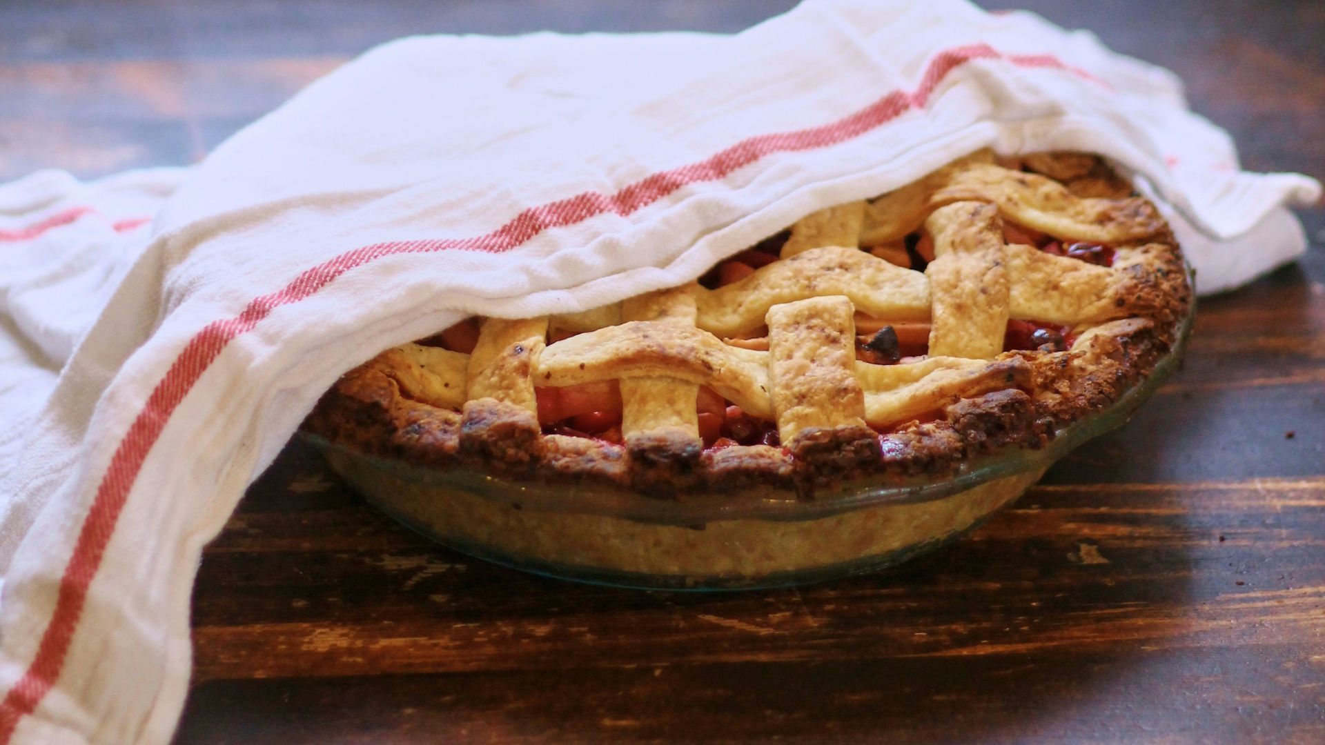 A pie sitting on top of a wooden table next to a window