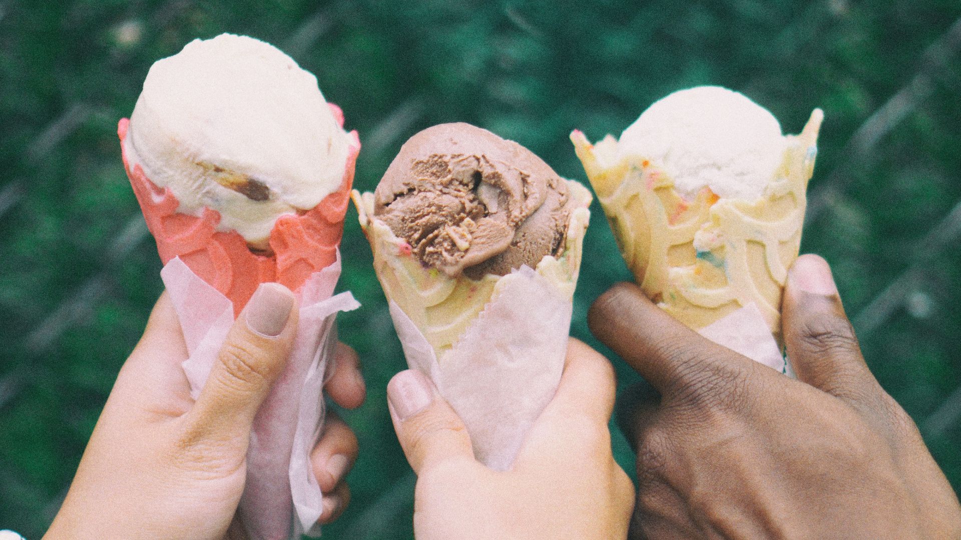 three people holding ice cream cones in their hands