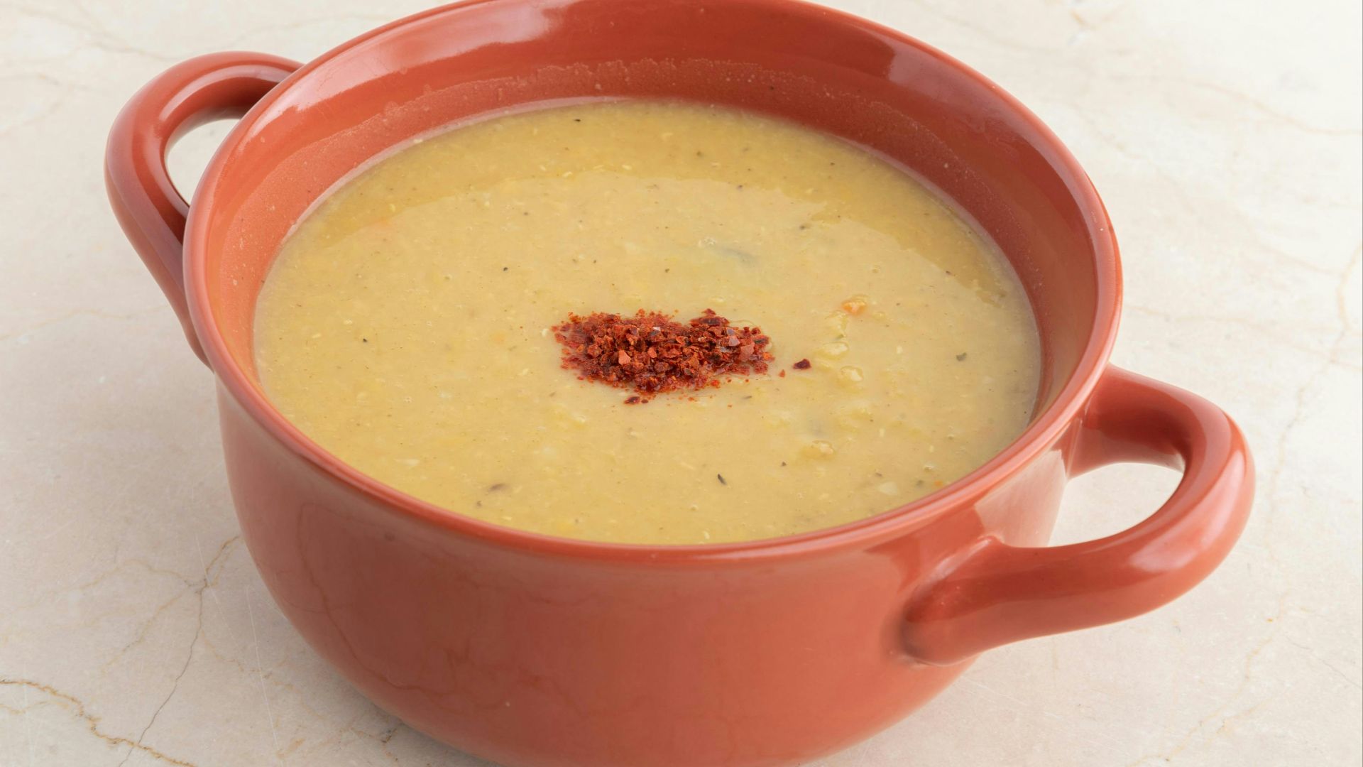 A red bowl filled with soup on top of a white counter