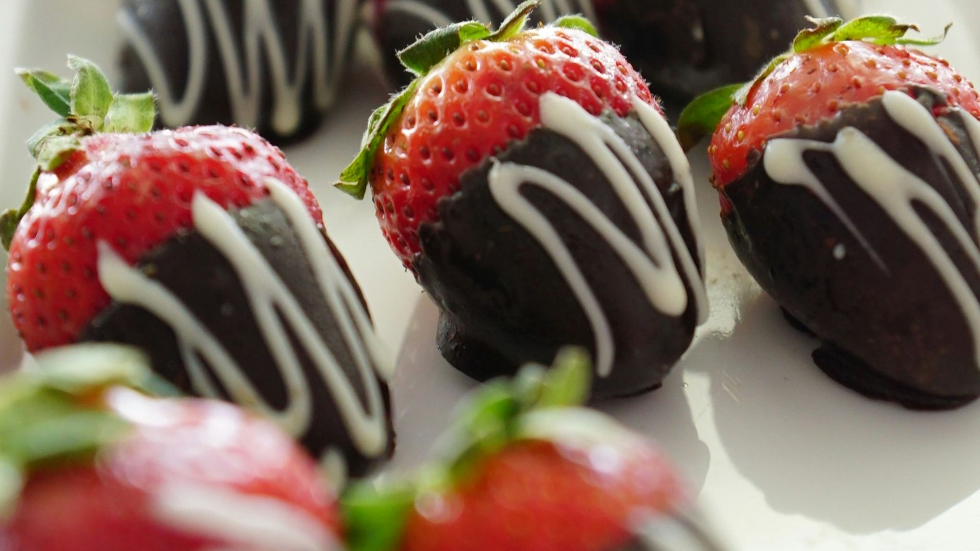 a plate of chocolate covered strawberries on a table