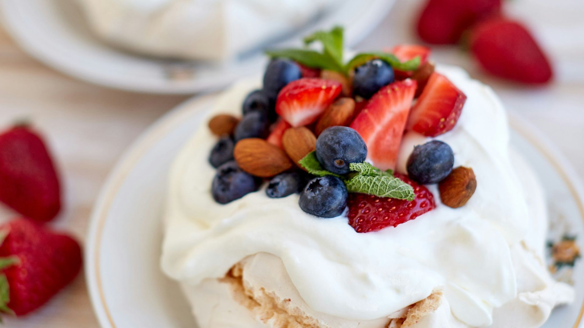two desserts on a white plate with strawberries and blueberries