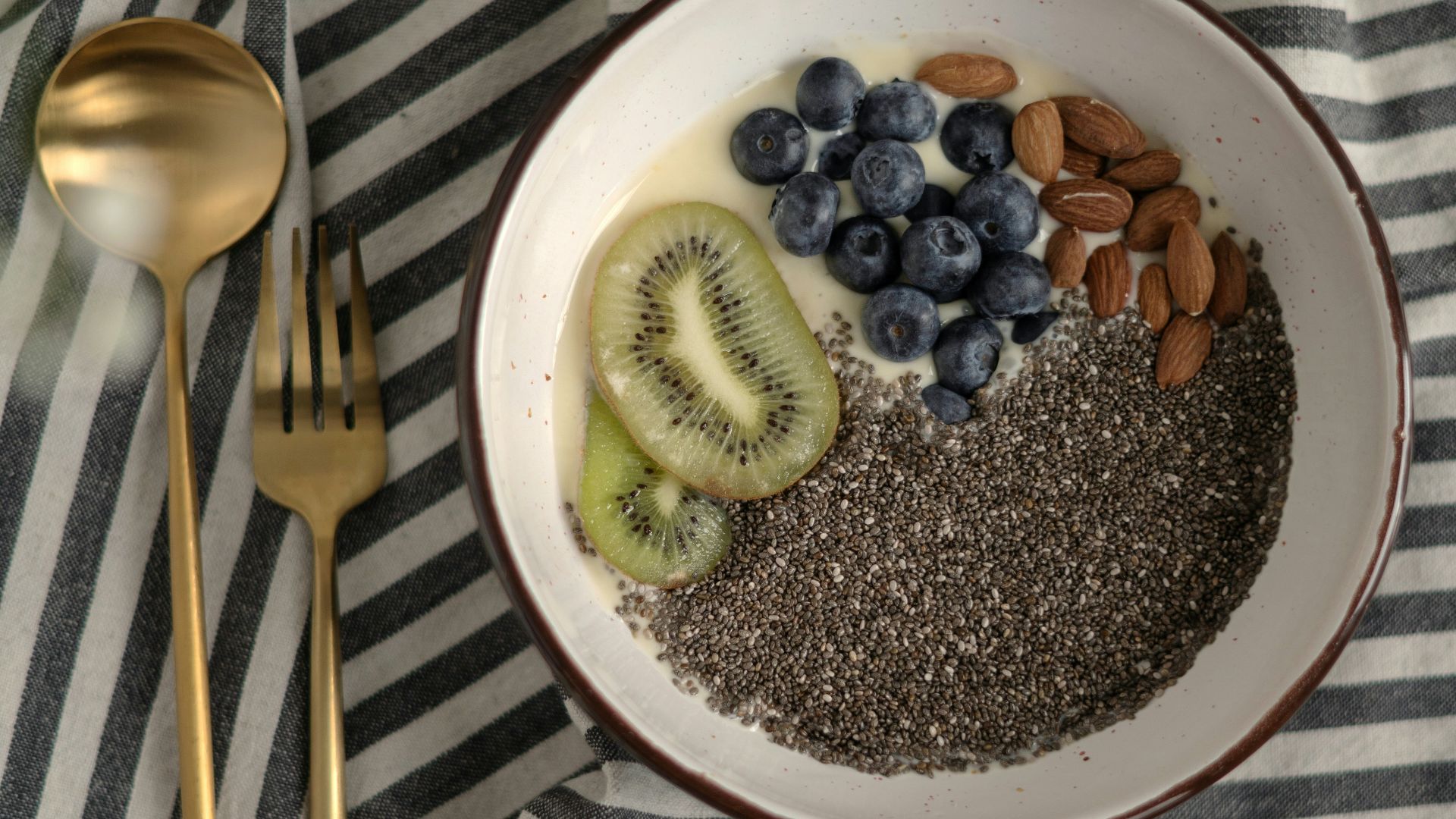 a bowl of cereal with kiwis, bananas, and blueberries