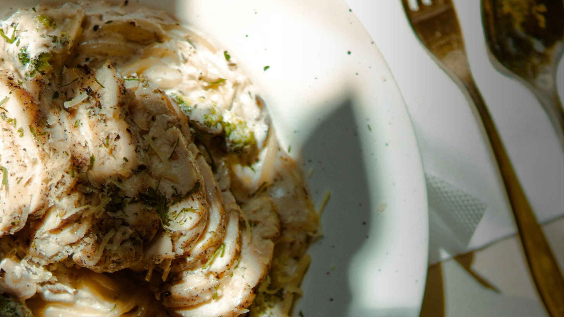 Pasta dish with utensils on a white surface.