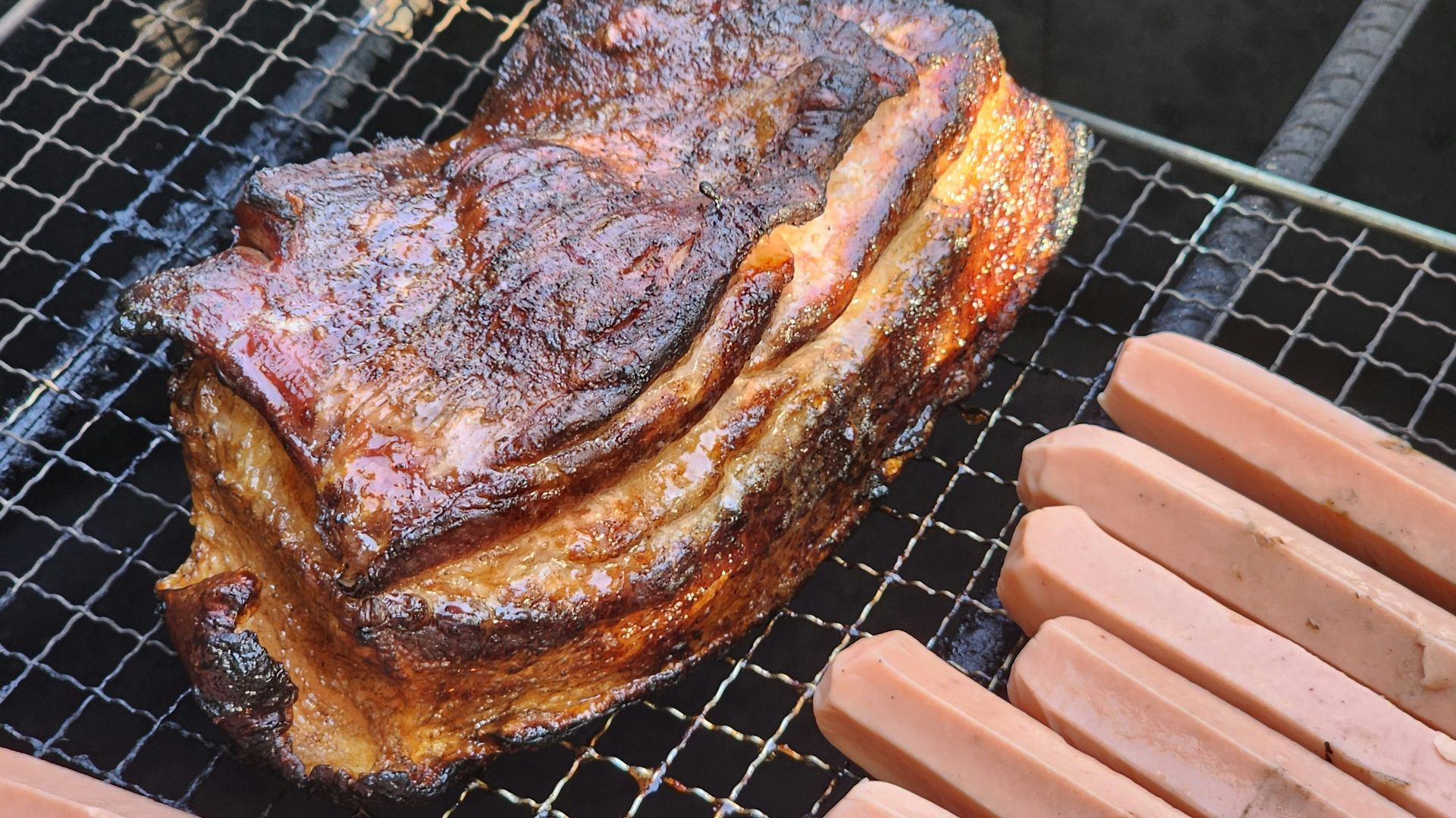 a steak and hotdogs are cooking on a grill