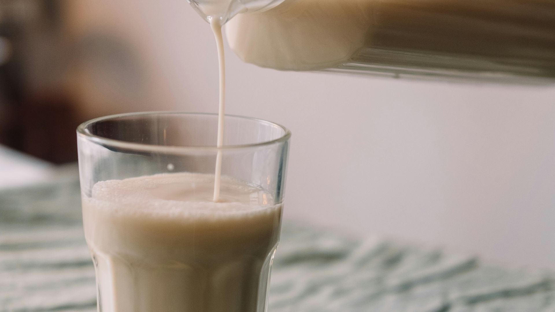 a person pouring milk into a glass on top of a bed