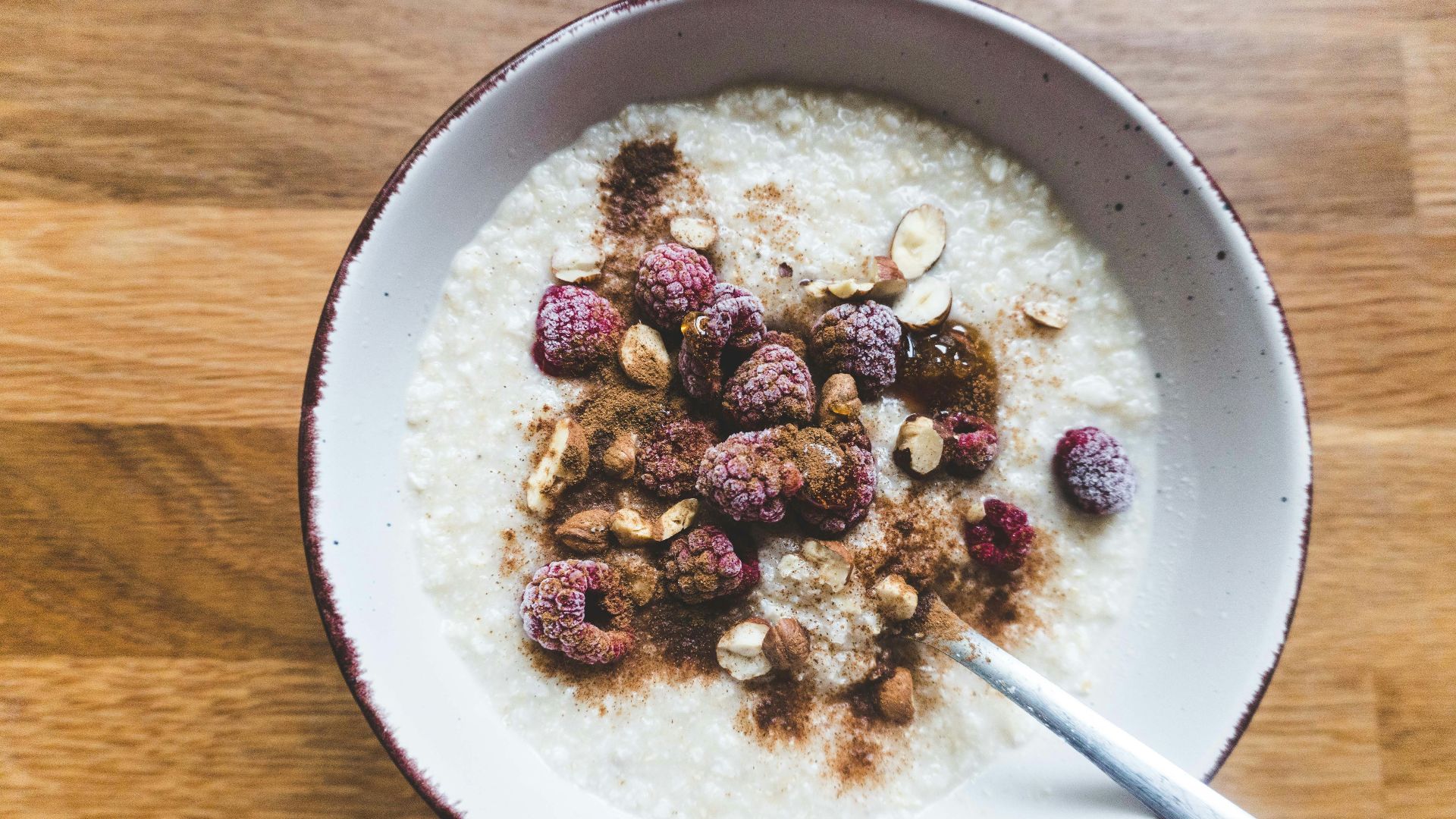 a bowl of oatmeal topped with raspberries and nuts