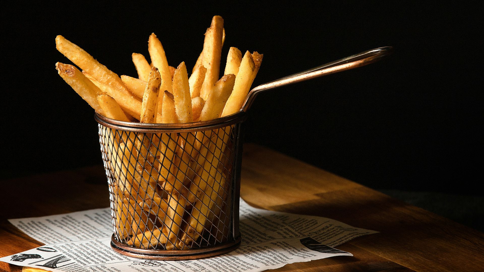 a basket of french fries sitting on top of a wooden table