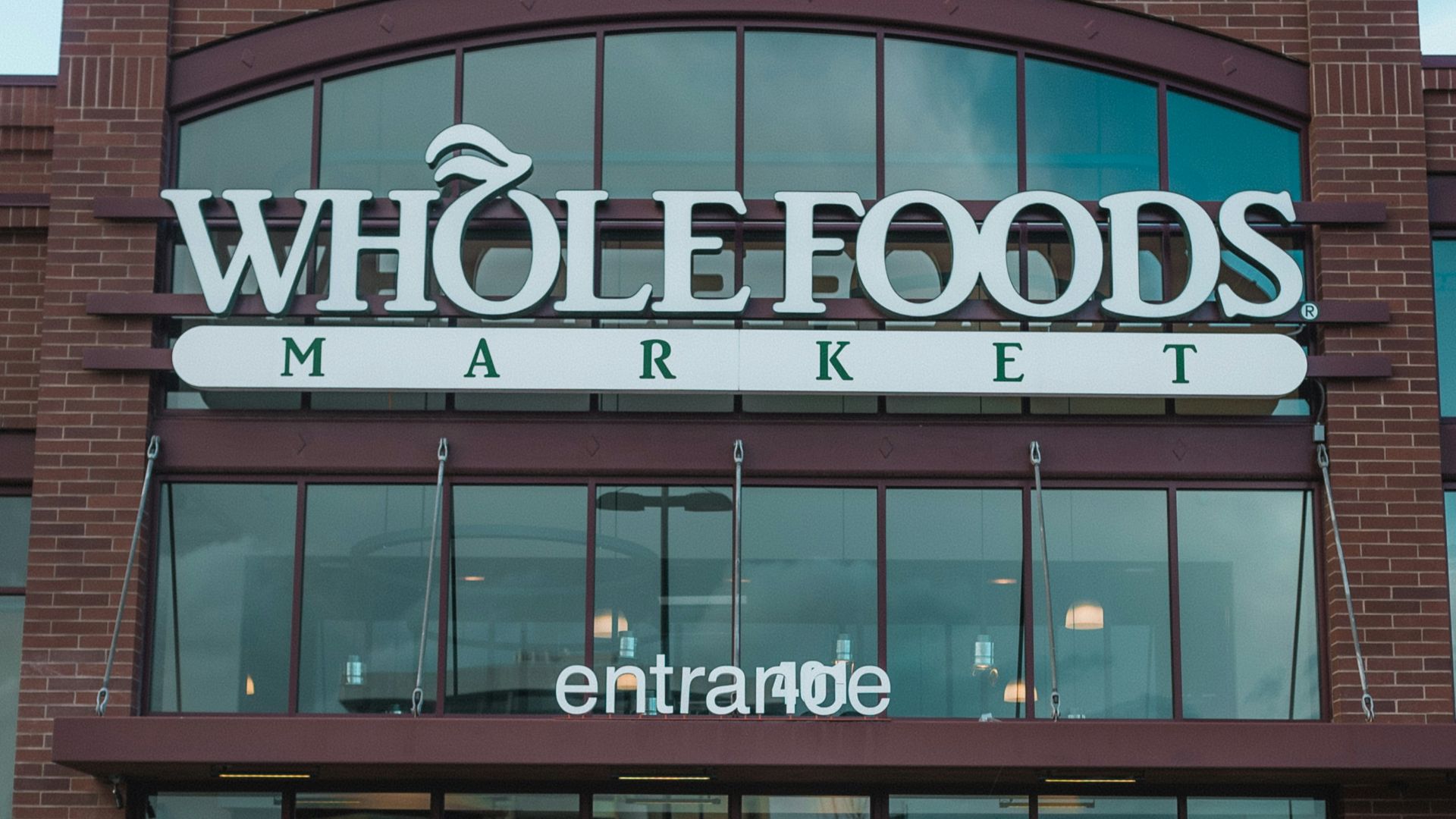 man in blue denim jacket and blue denim jeans walking on sidewalk near brown and white