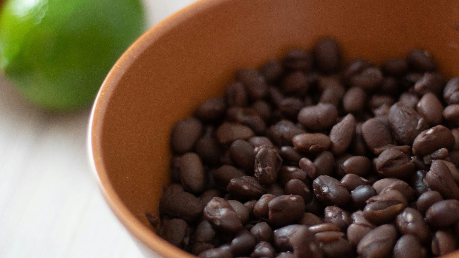 a bowl filled with black beans next to limes