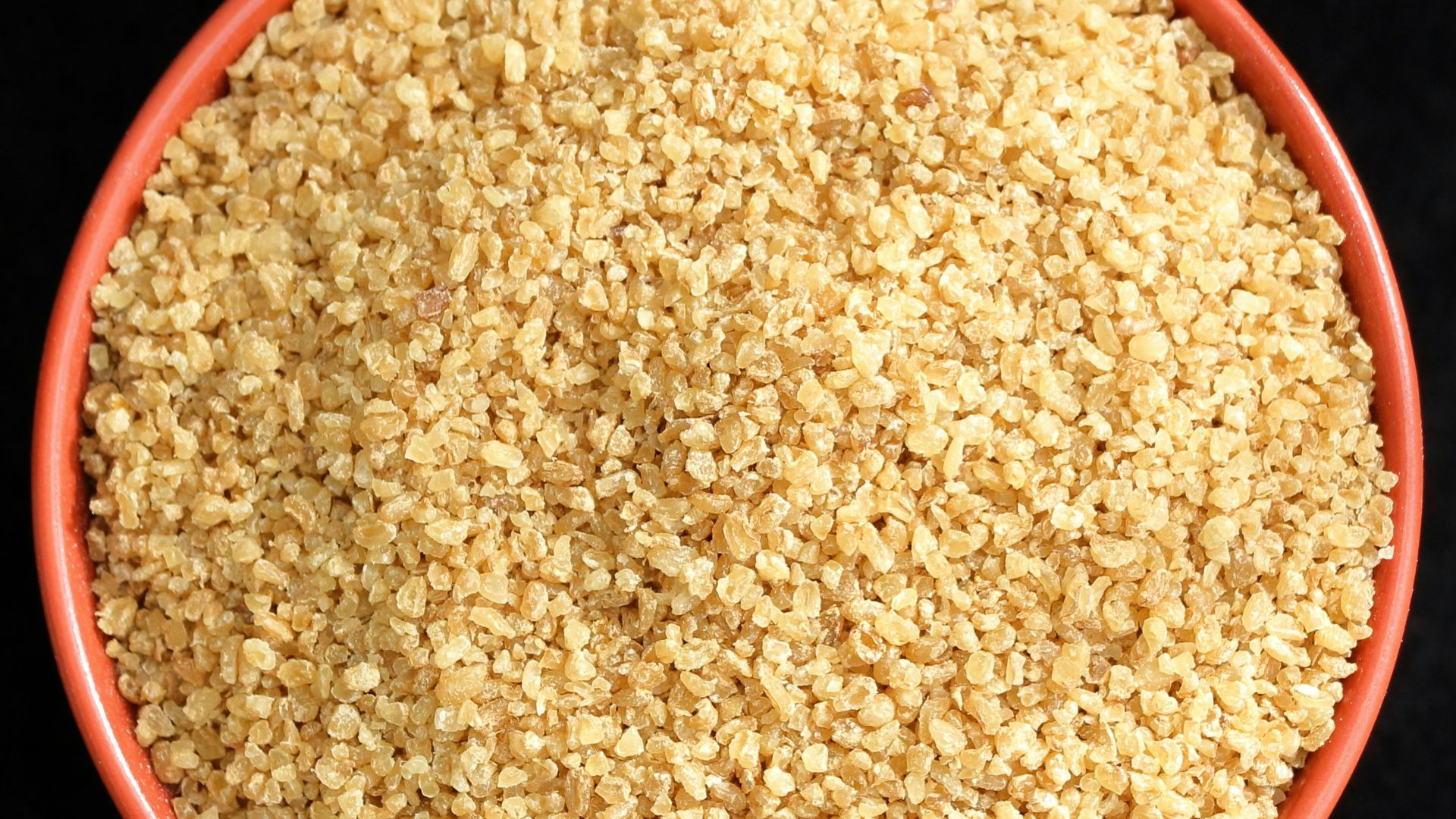 a bowl of sesame seeds on a black background