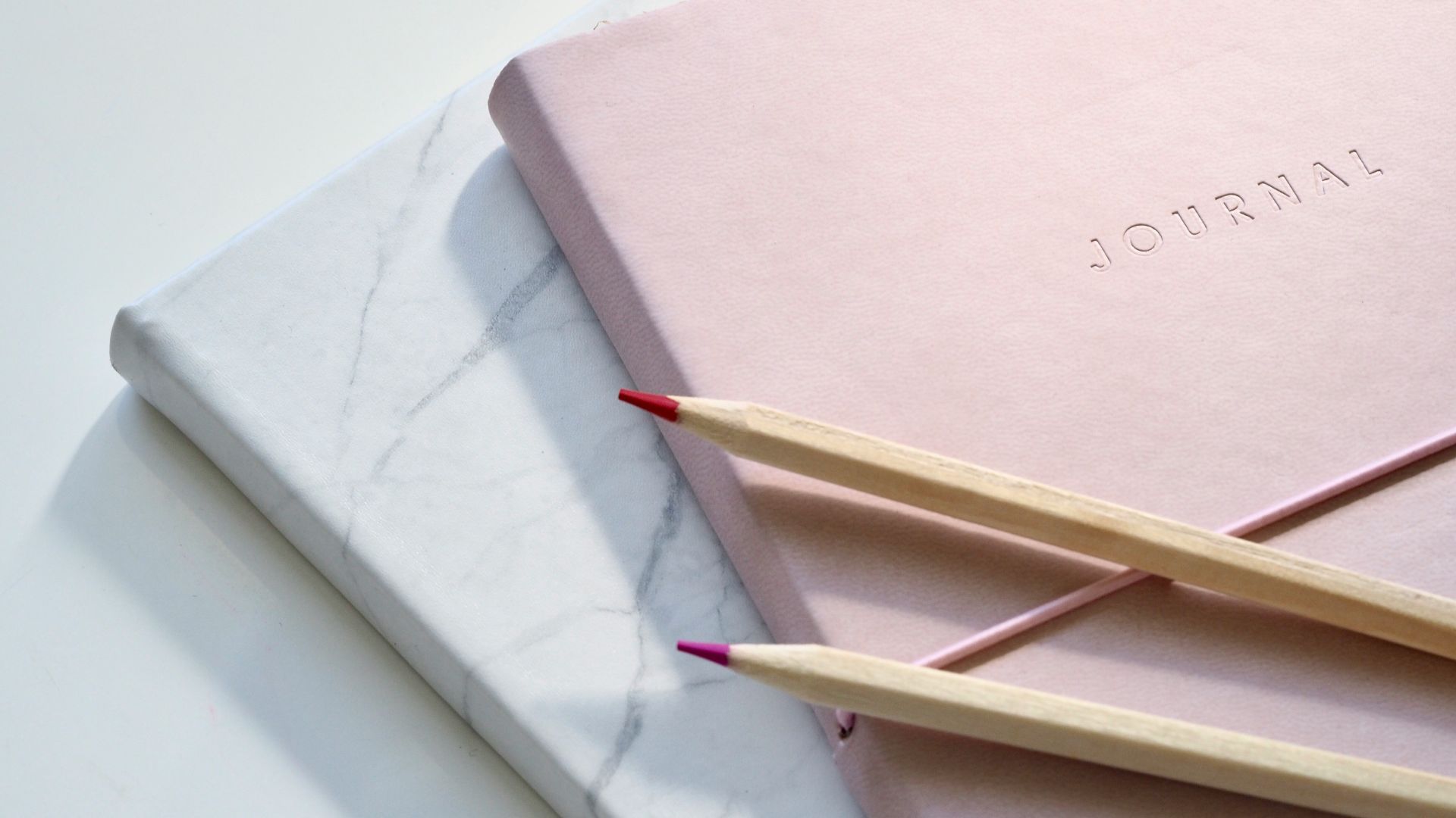 red and purple coloring pencils on pink journal