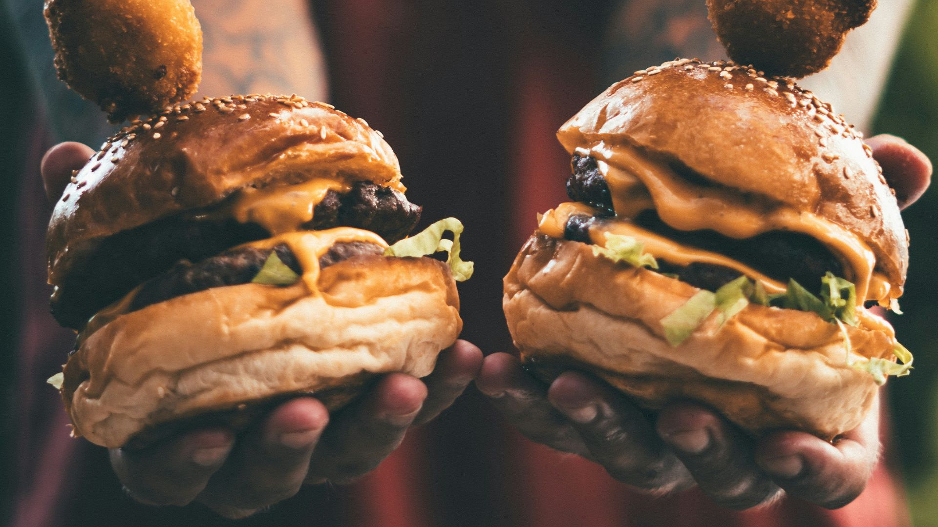 person holding two cheese hamburgers