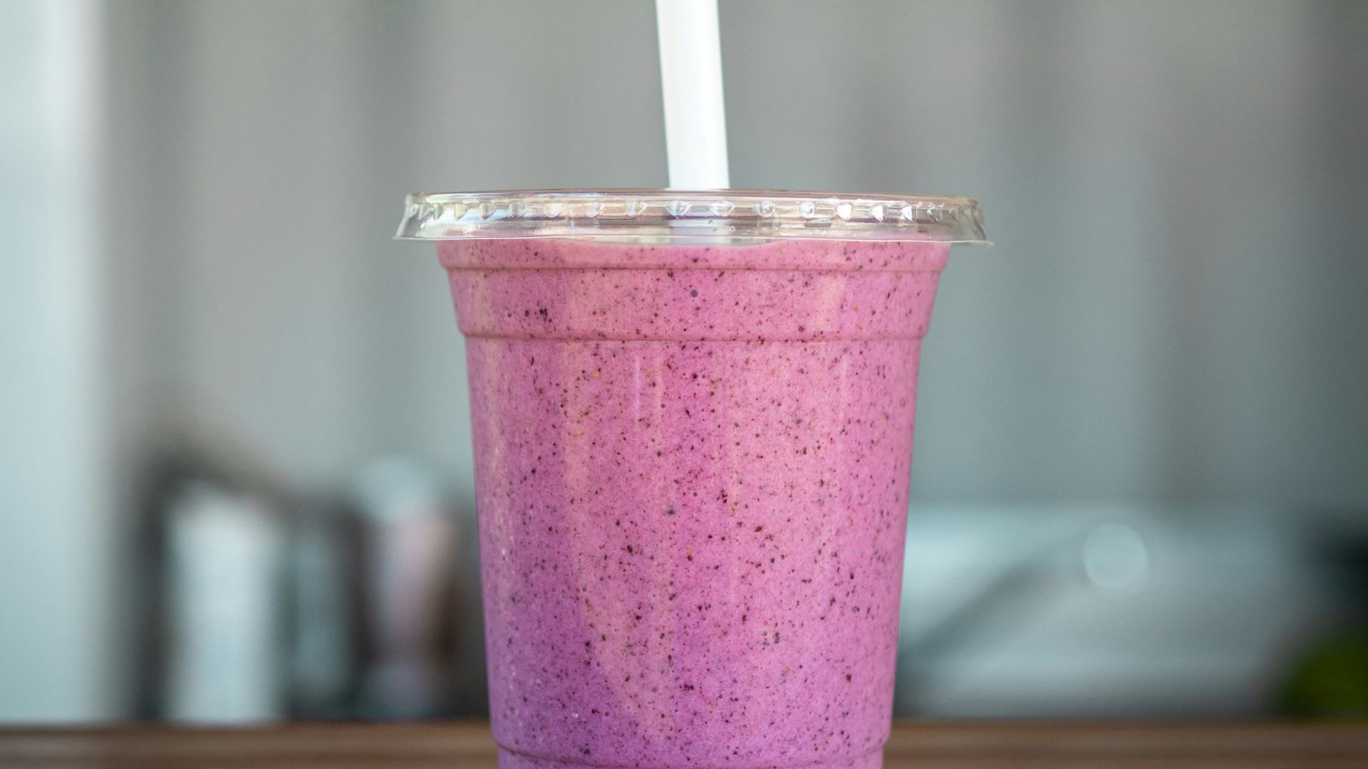 clear cup with straw on beige wooden surface