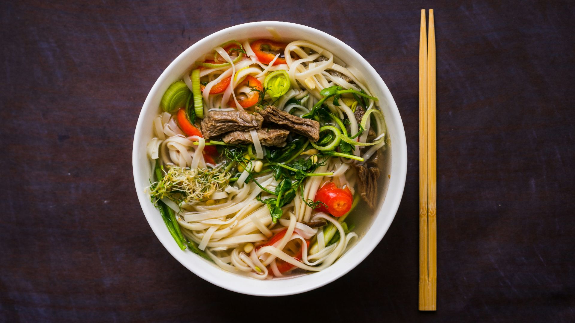 a bowl of noodle soup with chopsticks on the side