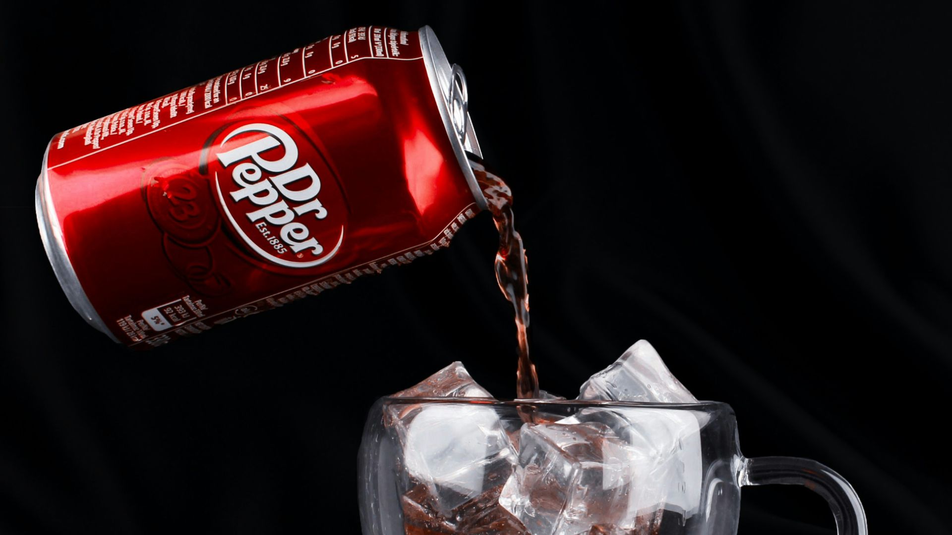 A can of coca cola being poured into a cup