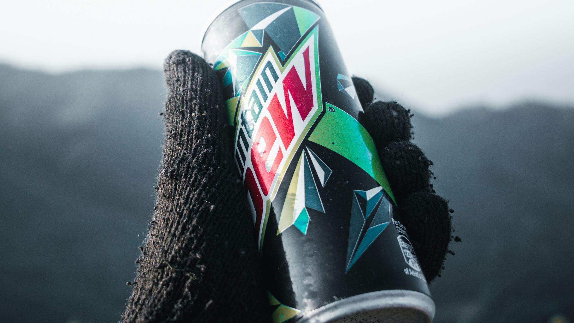 a hand holding a can of wnc on top of a mountain