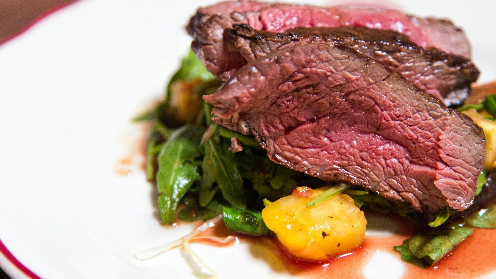 medium rare sliced steak in white ceramic plate