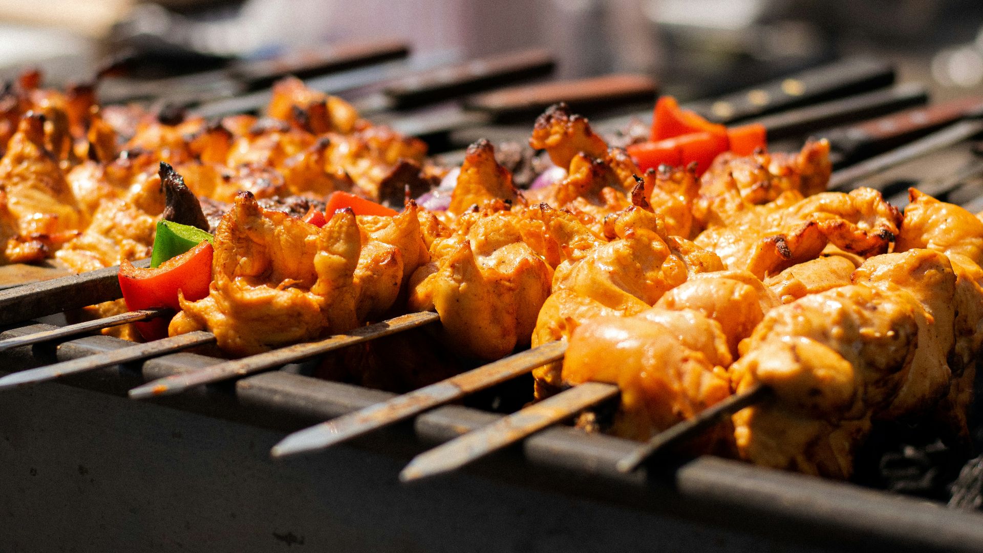 several skewers of chicken and vegetables on a grill