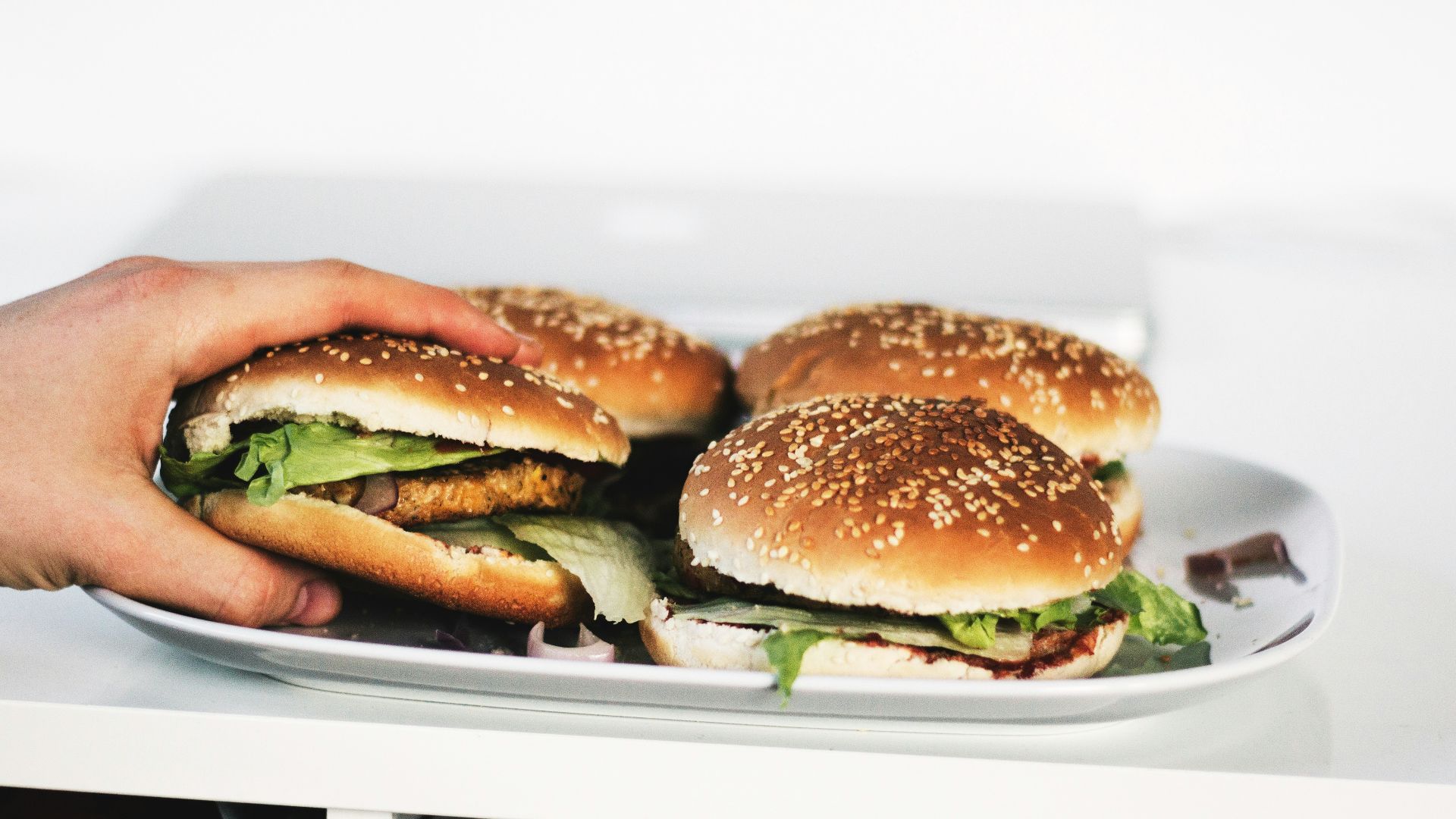 person holding hamburger on plate