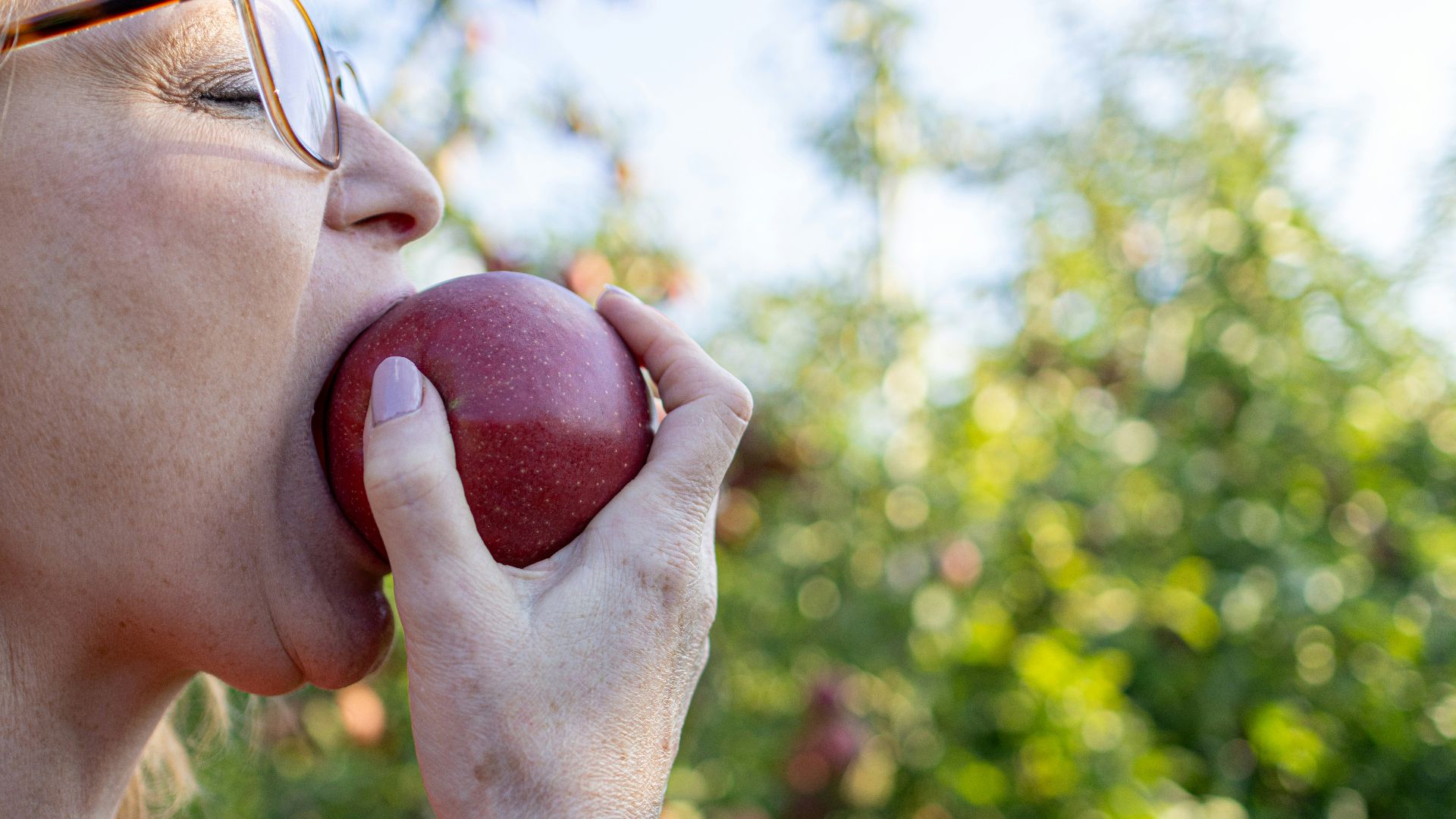 a woman eating an apple with her eyes closed