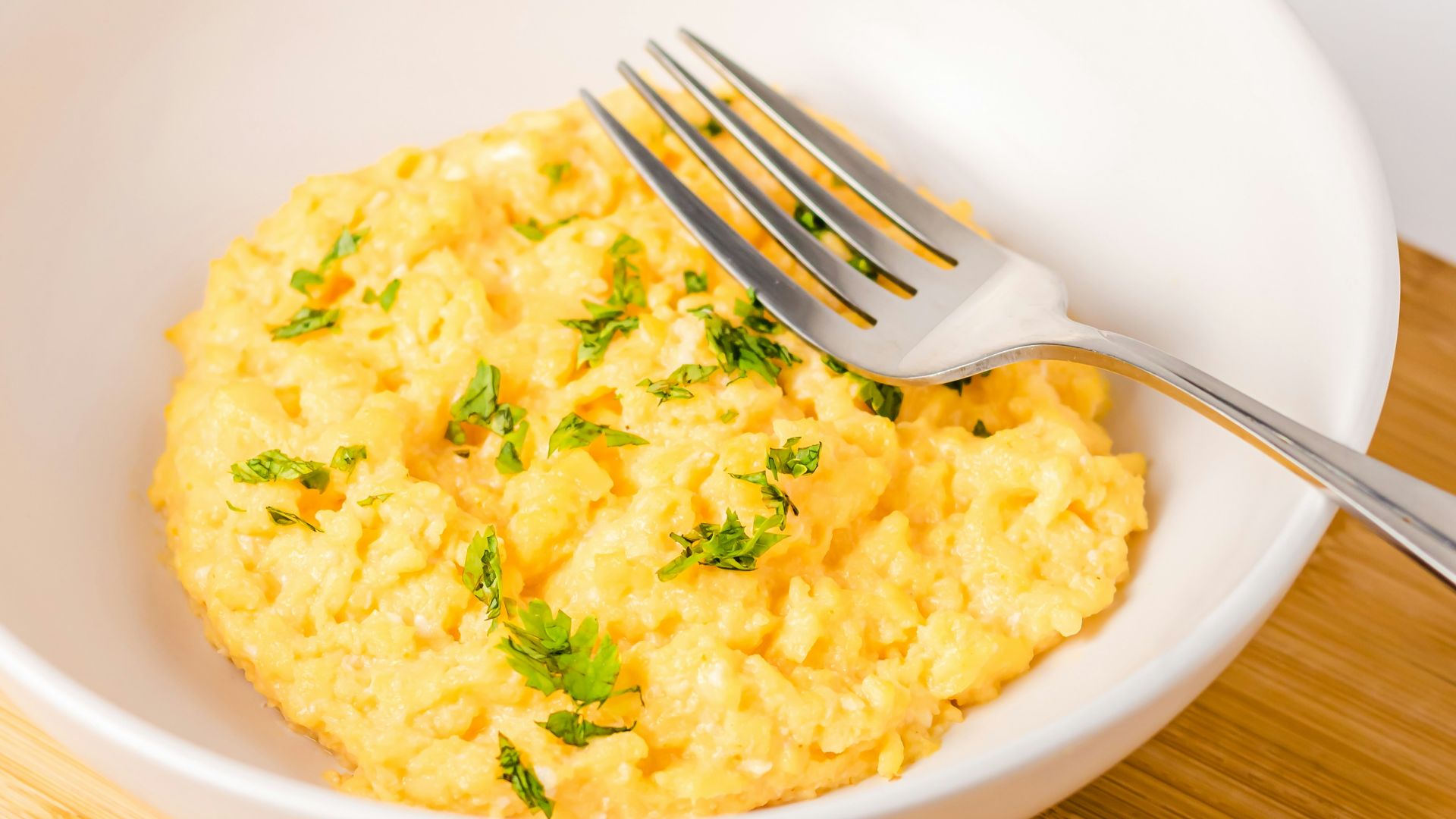a bowl of scrambled eggs next to a slice of bread