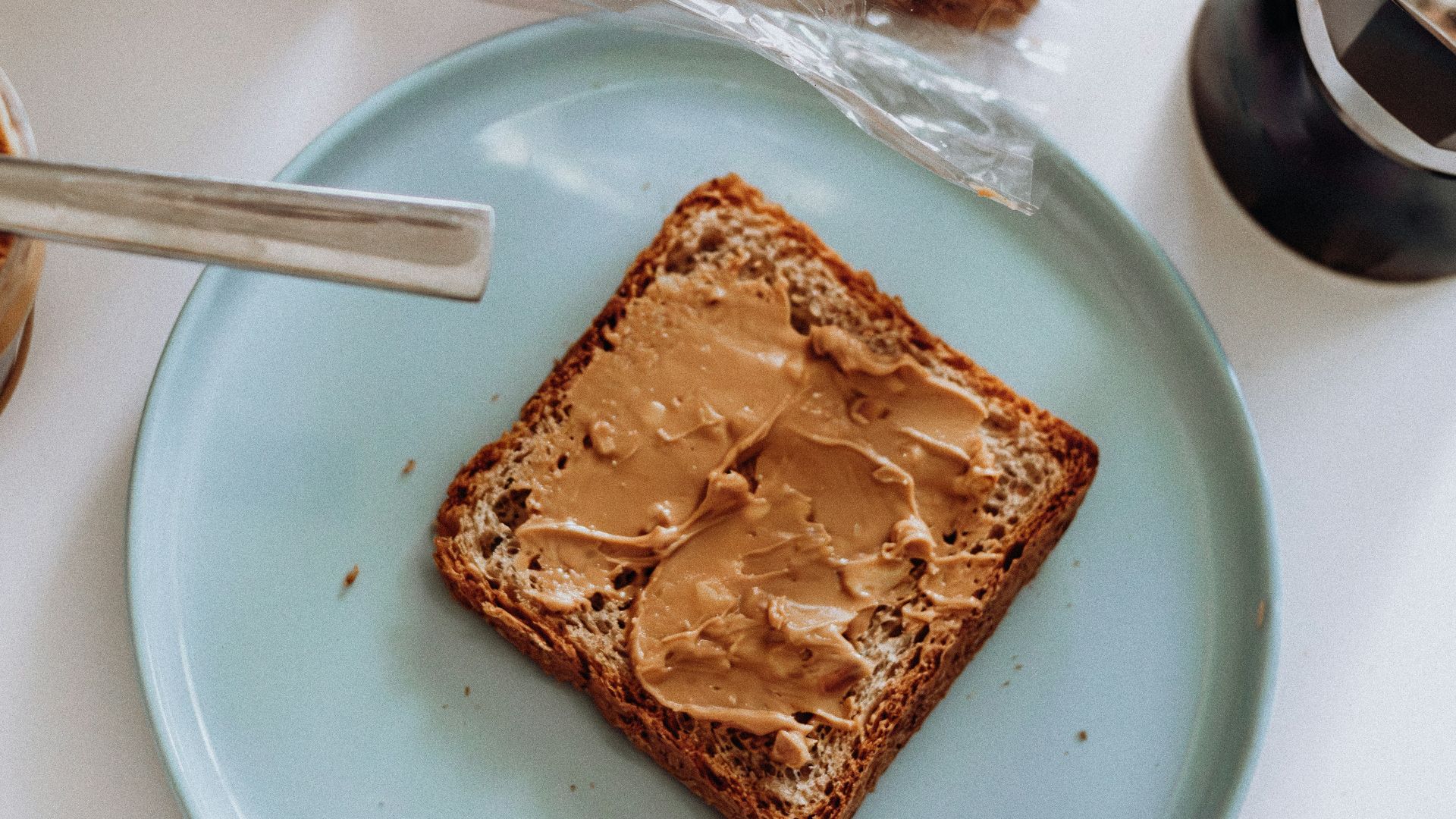 a blue plate topped with a piece of bread and peanut butter