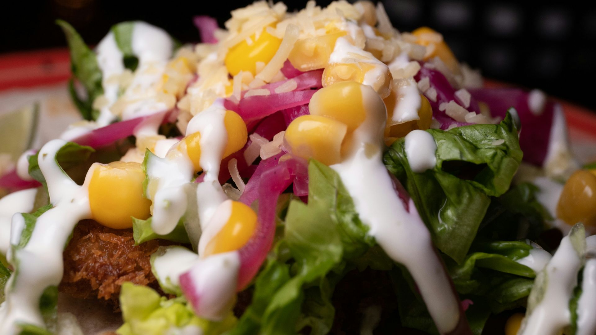 a taco filled with lettuce, corn, and dressing